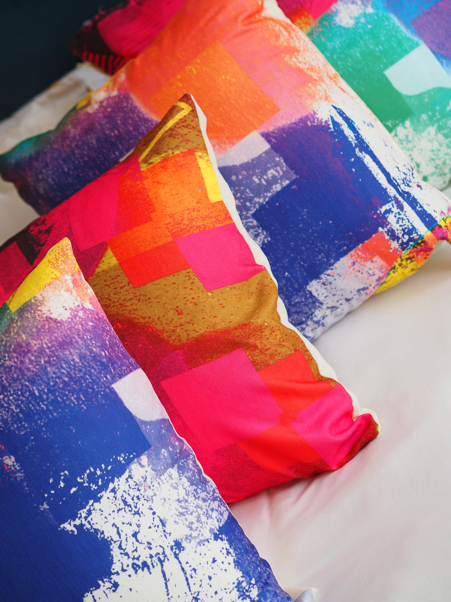 Colorful abstract patterned pillows on a white surface