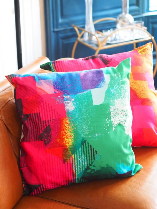 Colorful abstract-patterned pillows on a brown leather couch.