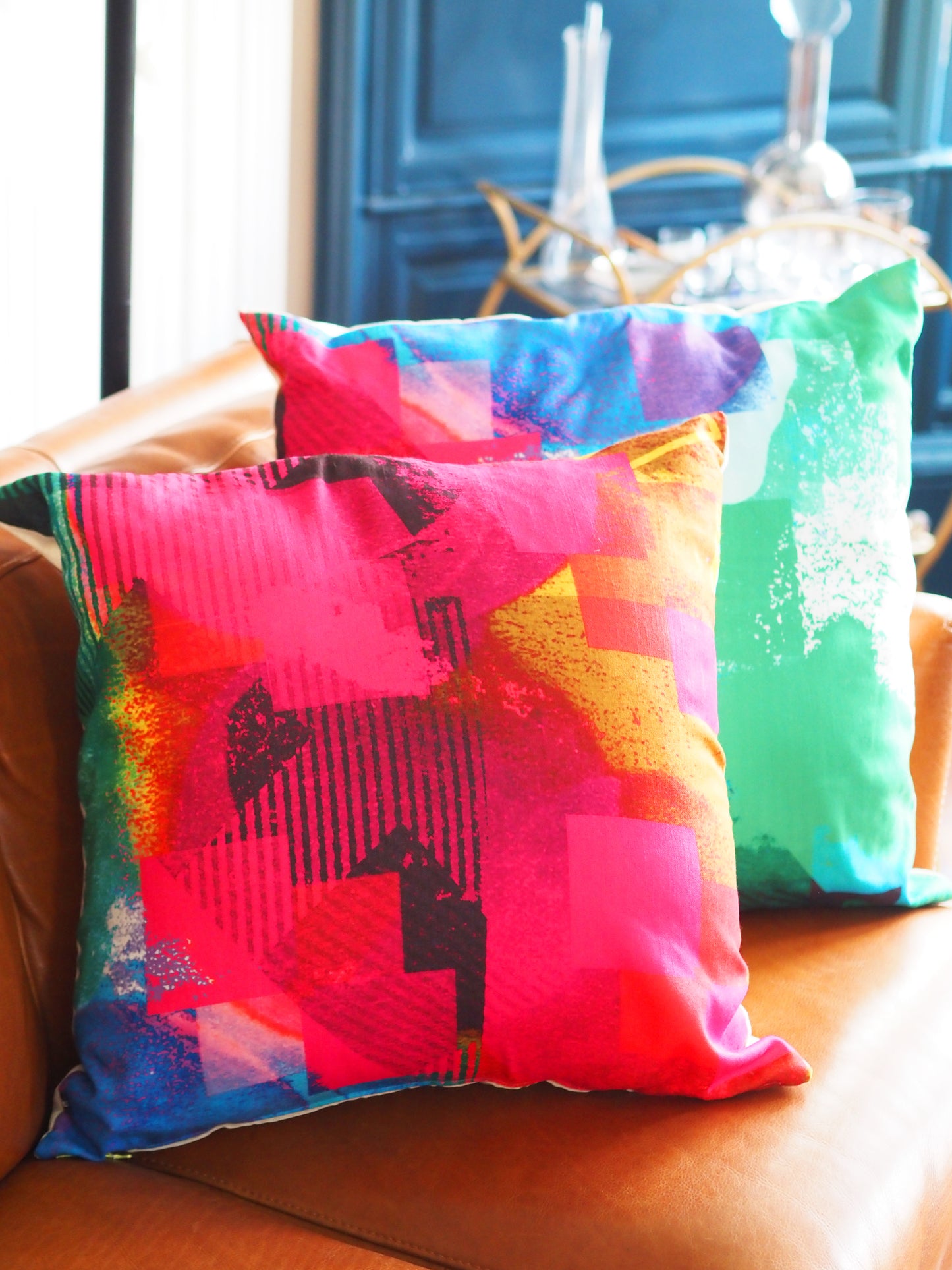Colorful abstract-patterned pillows on a couch with a blurred background