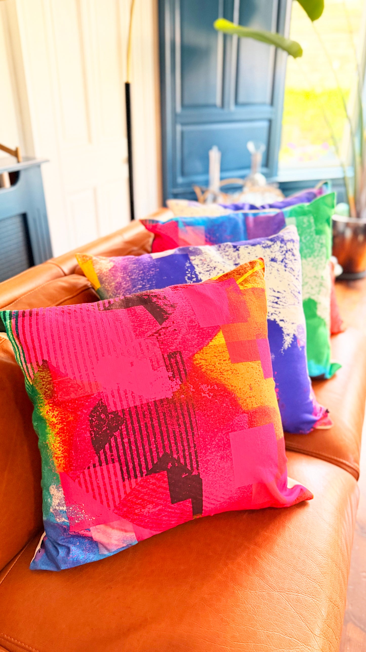 Colorful patterned cushions on a brown leather couch with a blurred indoor background