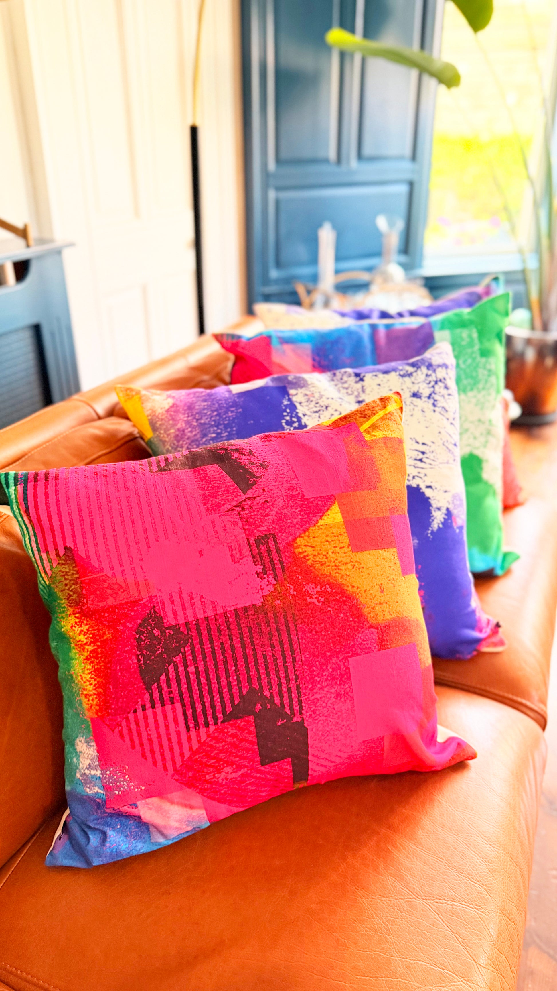 Colorful patterned cushions on a brown leather couch with a blurred indoor background