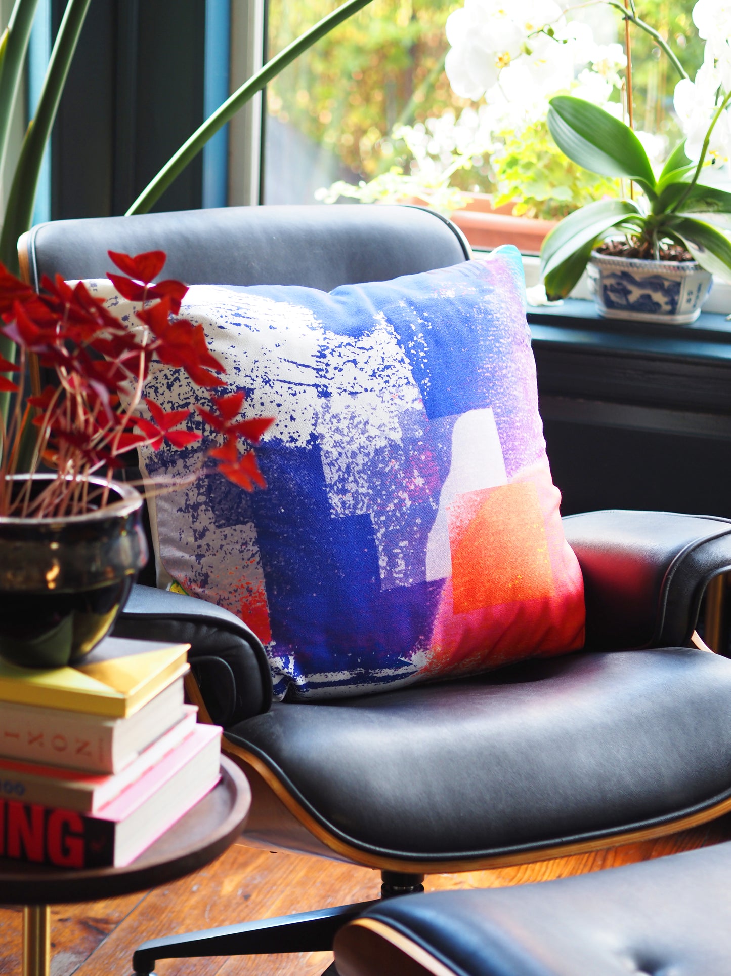 Decorative pillow on a chair with books and plants in the background