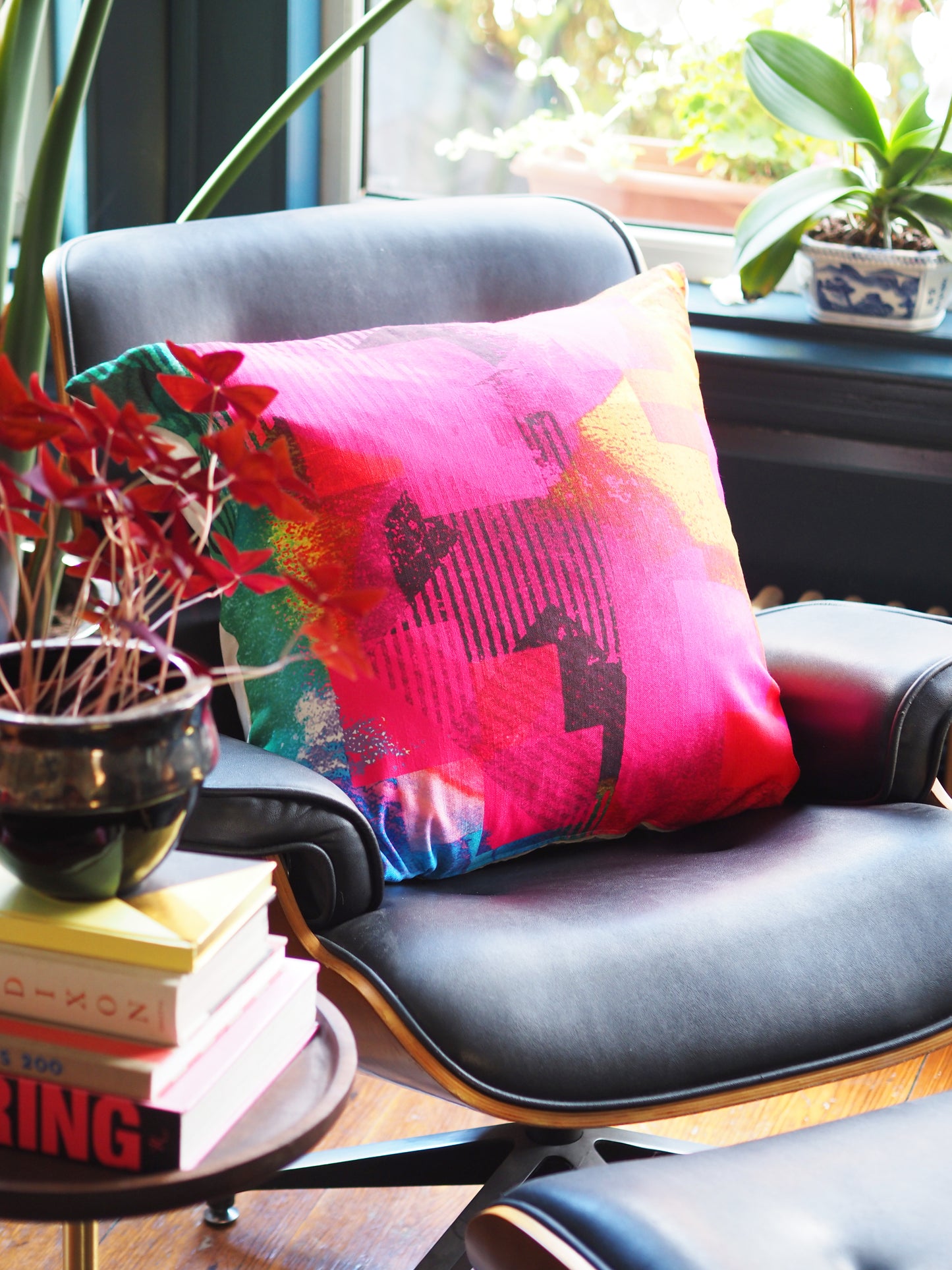 Decorative pillow on a chair with books and plants in a room