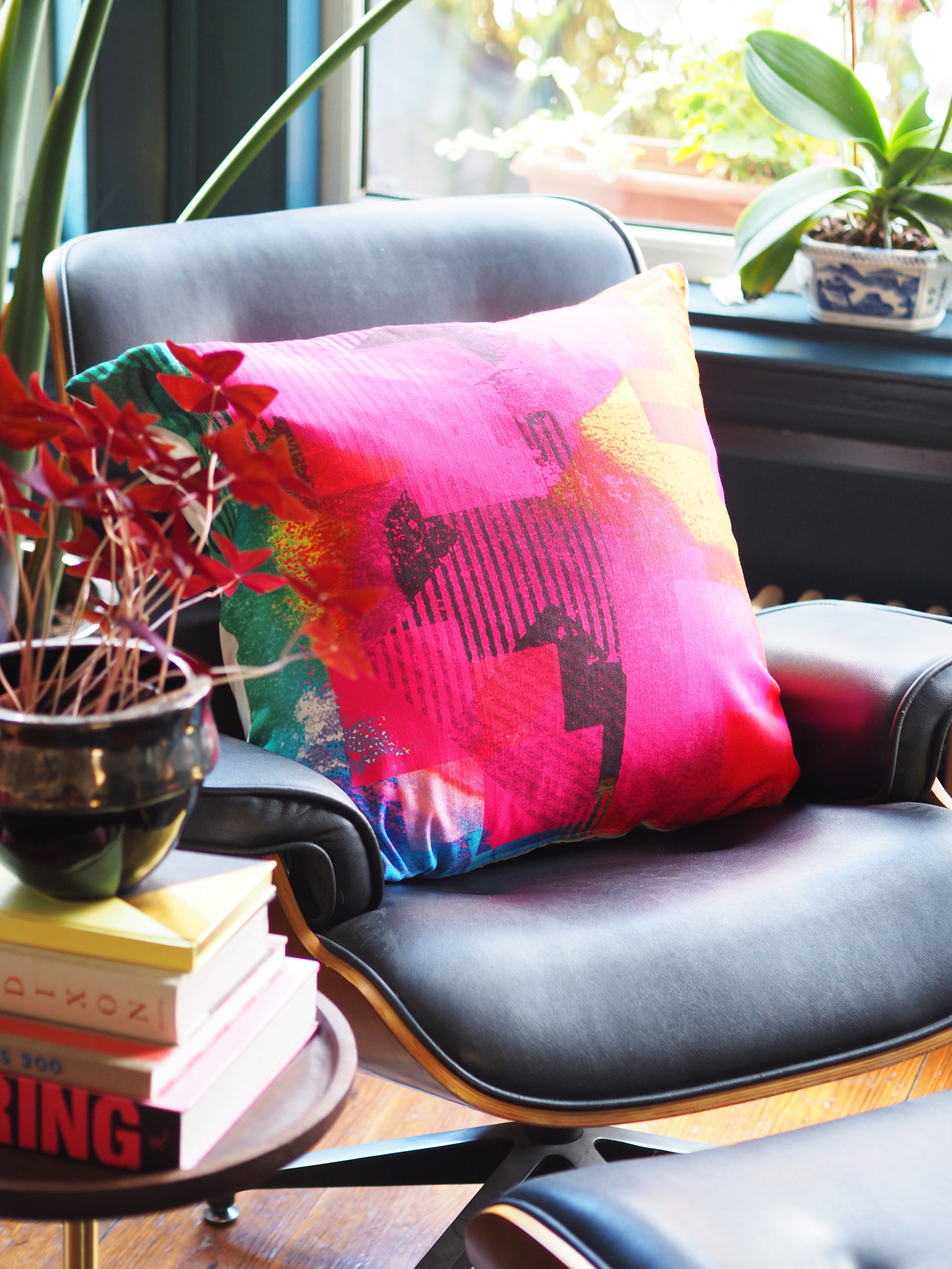 Decorative pillow on a chair with books and plants in a room