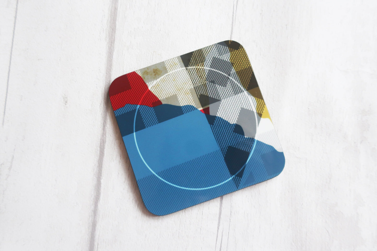 Colorful geometric patterned coaster on a white wooden surface