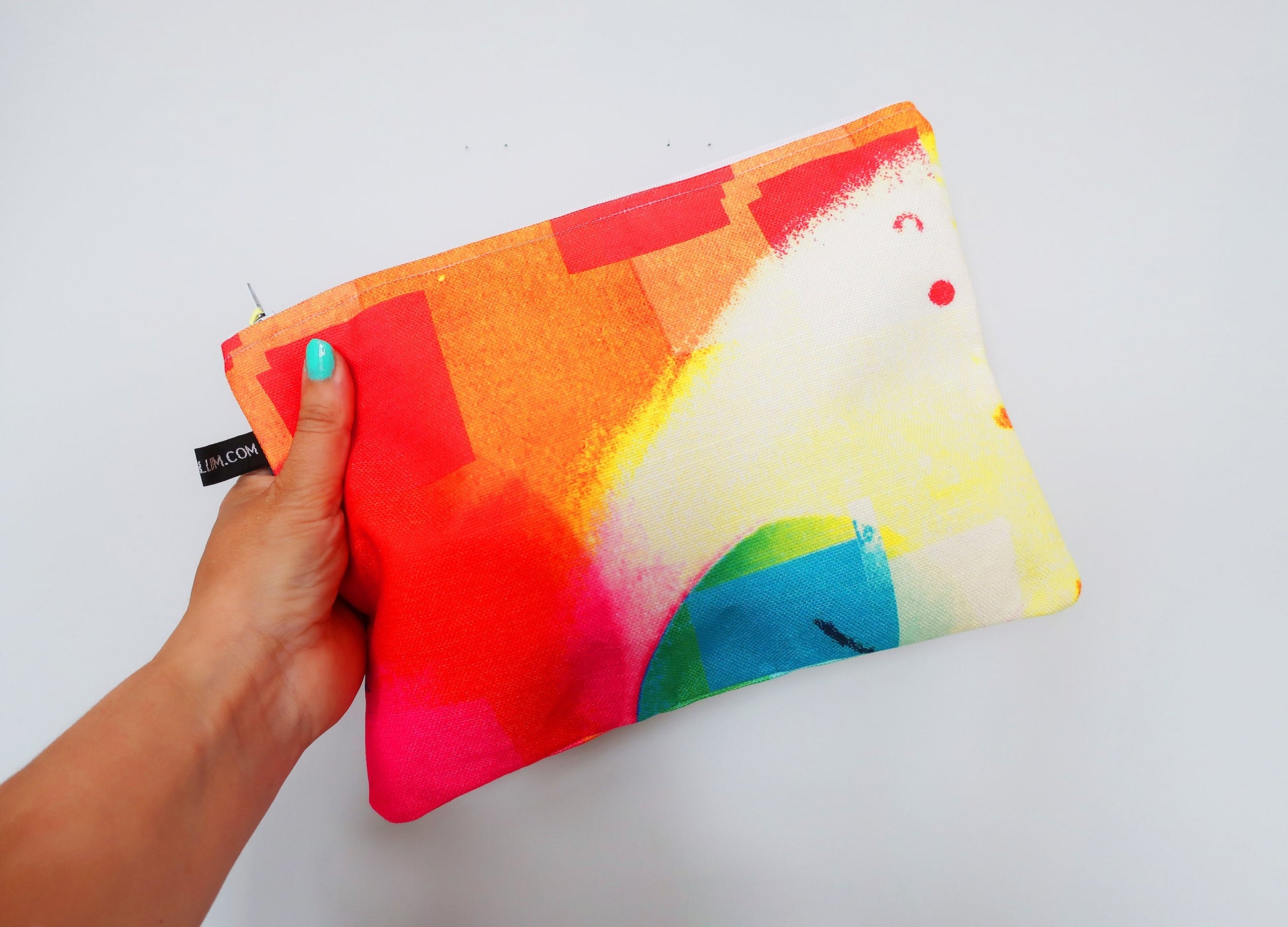 Colorful pouch held by a hand on a white background