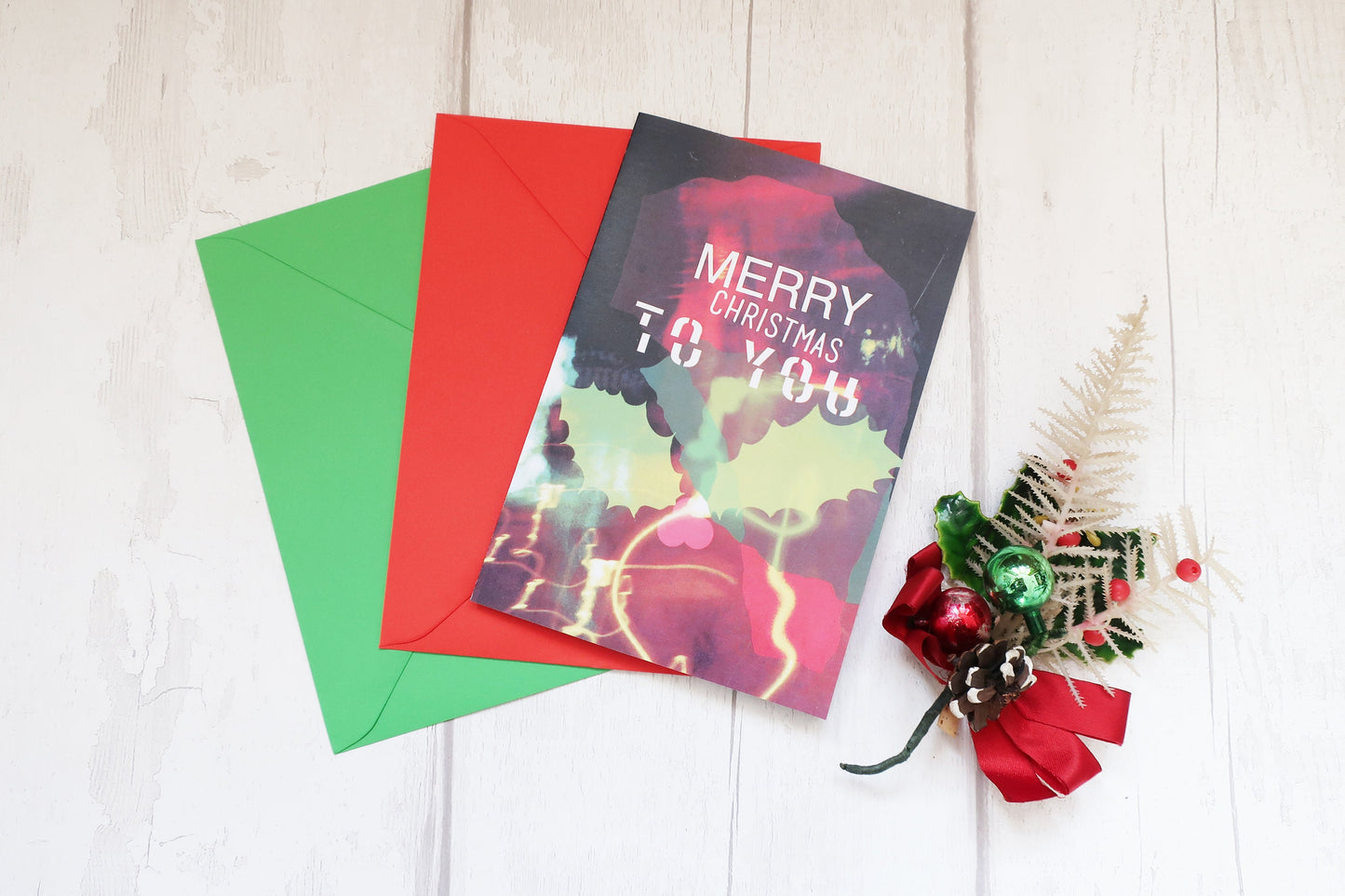 Colorful Christmas card with envelopes and decorative elements on a light wooden surface
