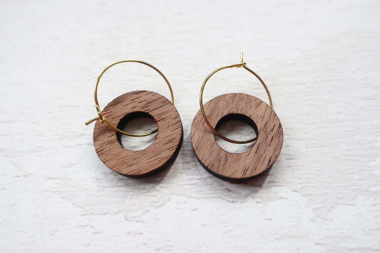 Wooden hoop earrings on a textured white surface