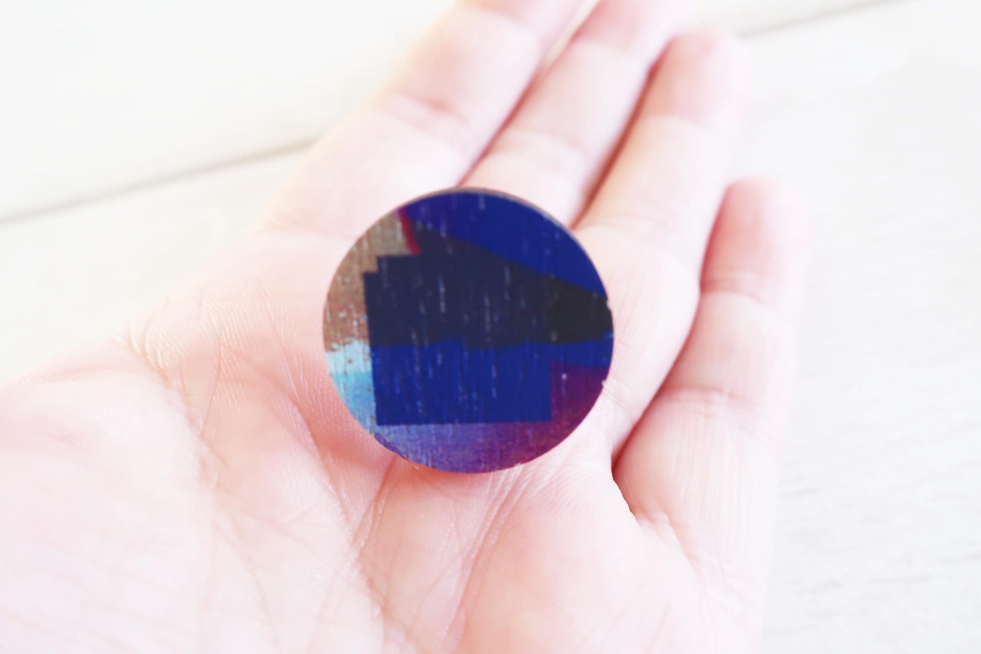 Round, multicolored ring held in a hand against a white background