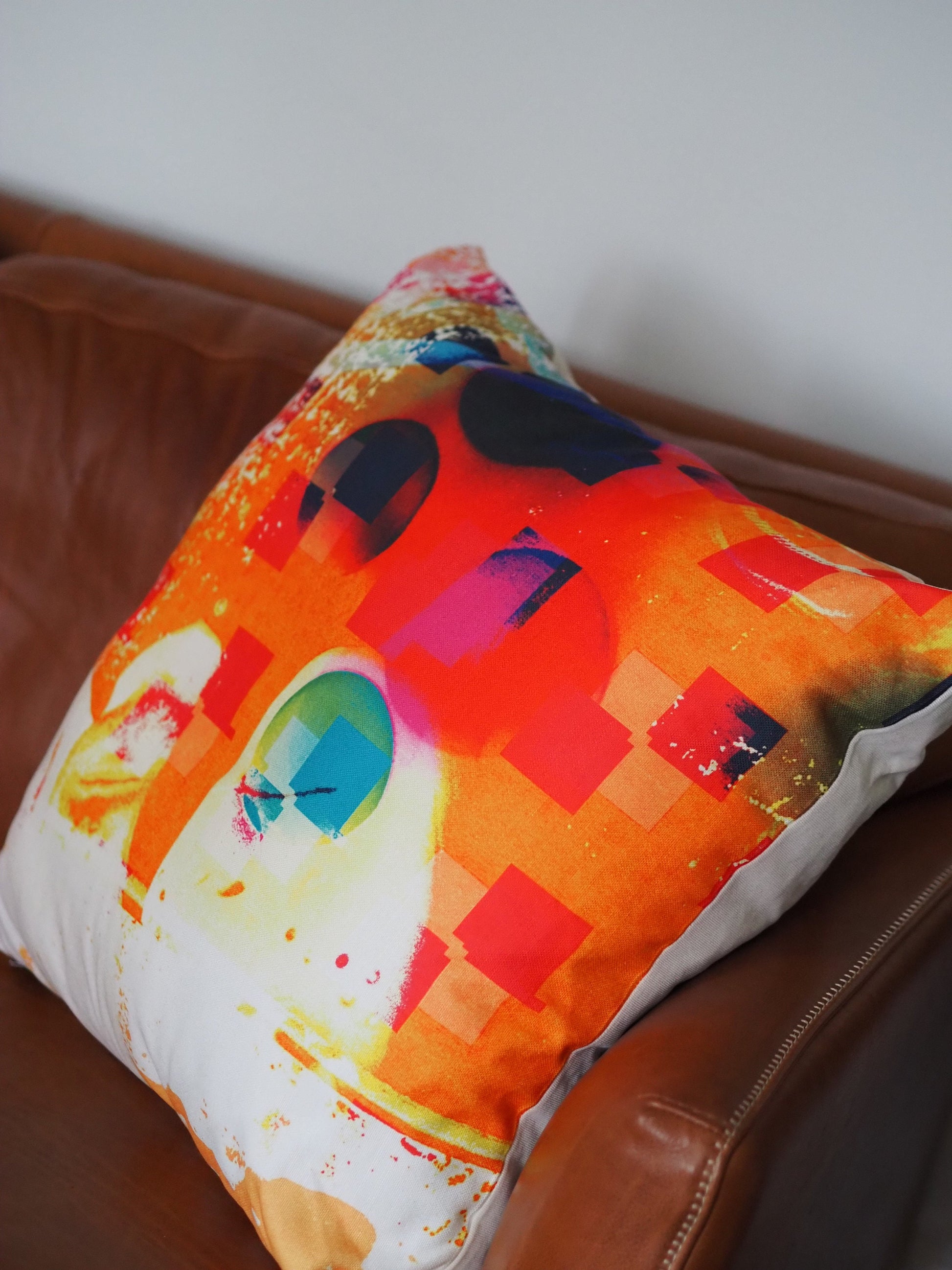 Colorful pillow with abstract design on a brown leather couch