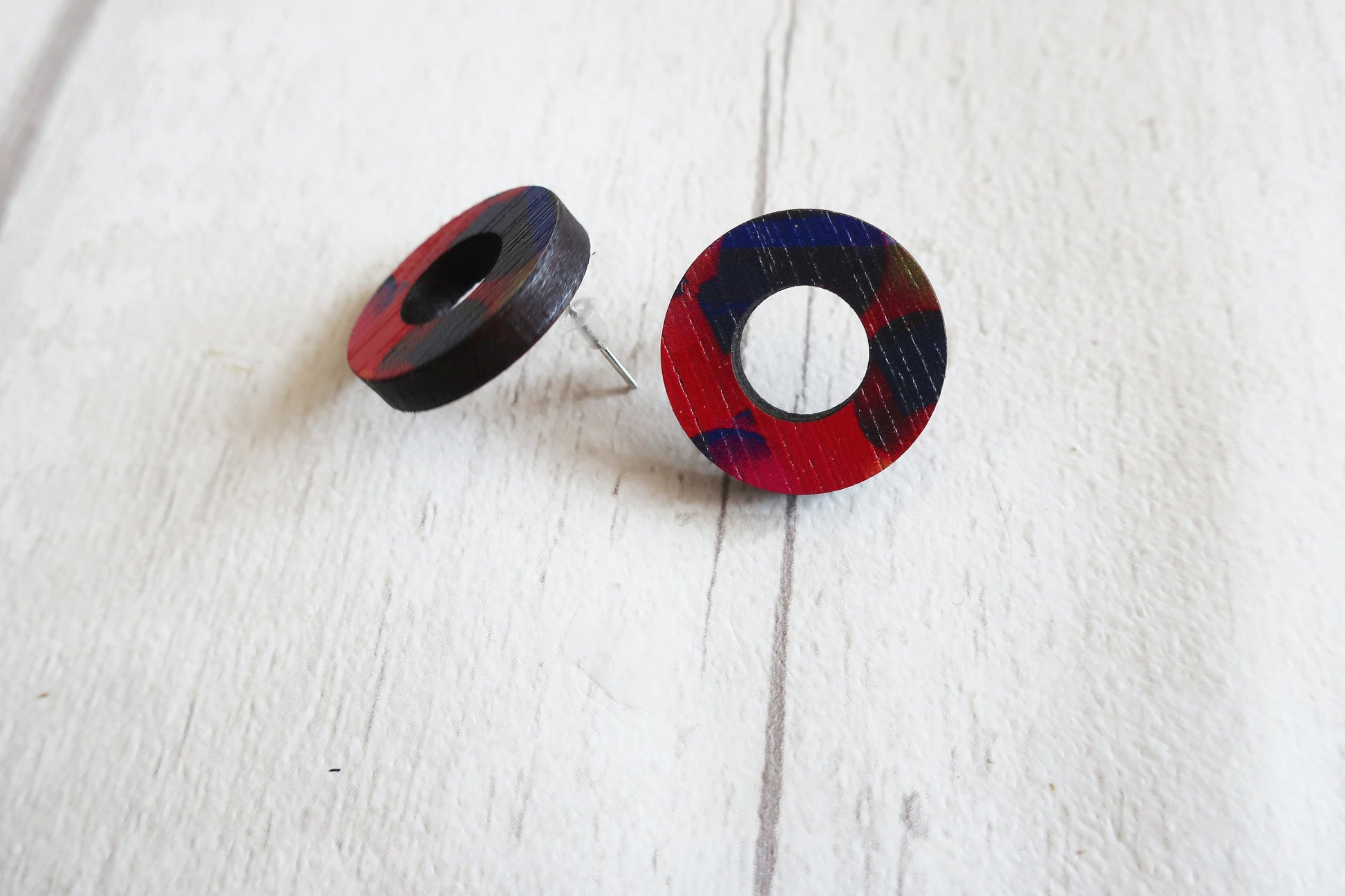 Pair of round earrings with red and blue plaid pattern on a white background