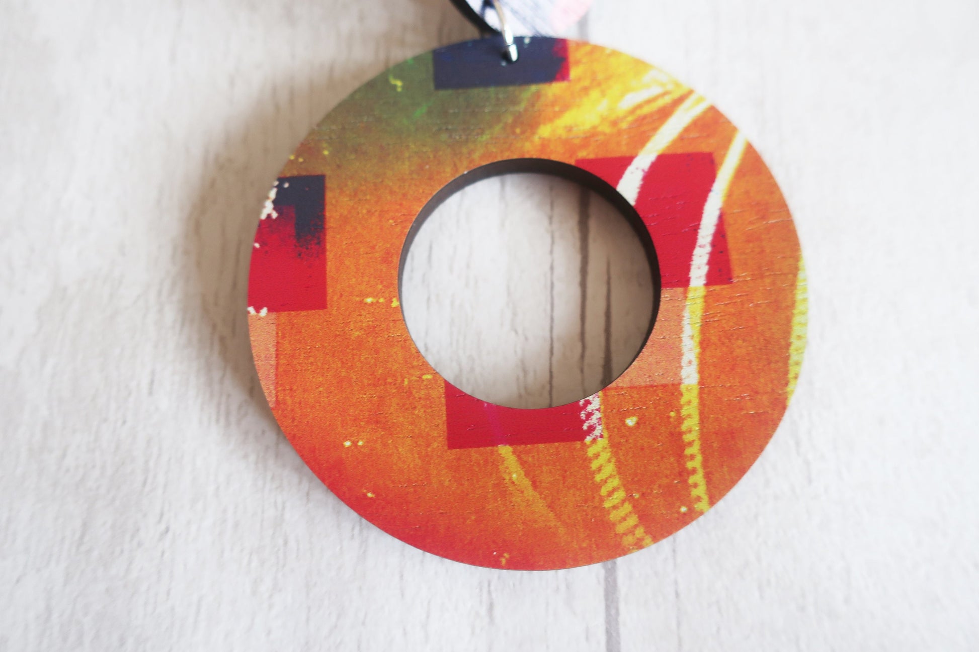 Colorful circular earring with a hole in the center on a white background
