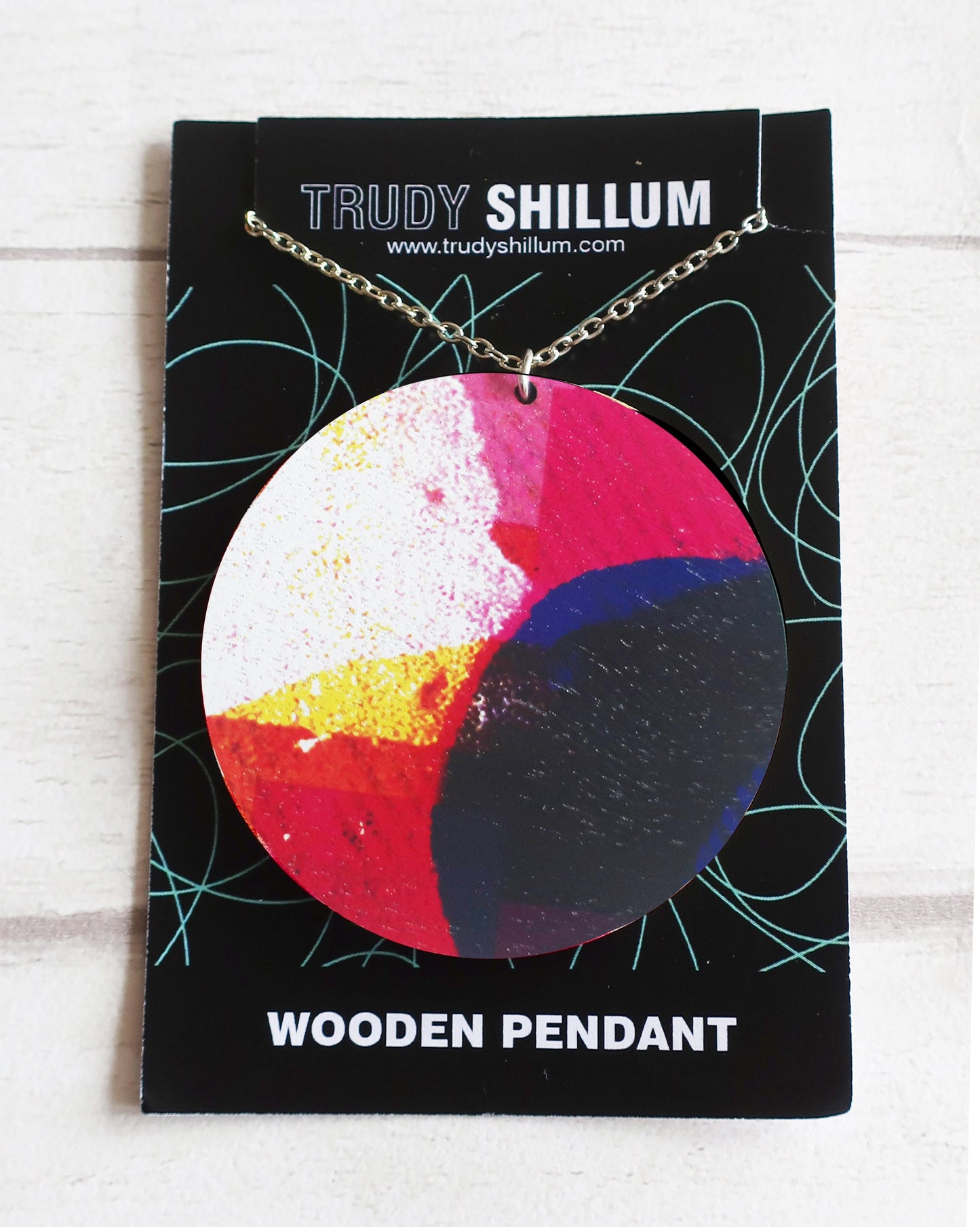 Colorful wooden pendant on a Trudy Shillum card with a white background