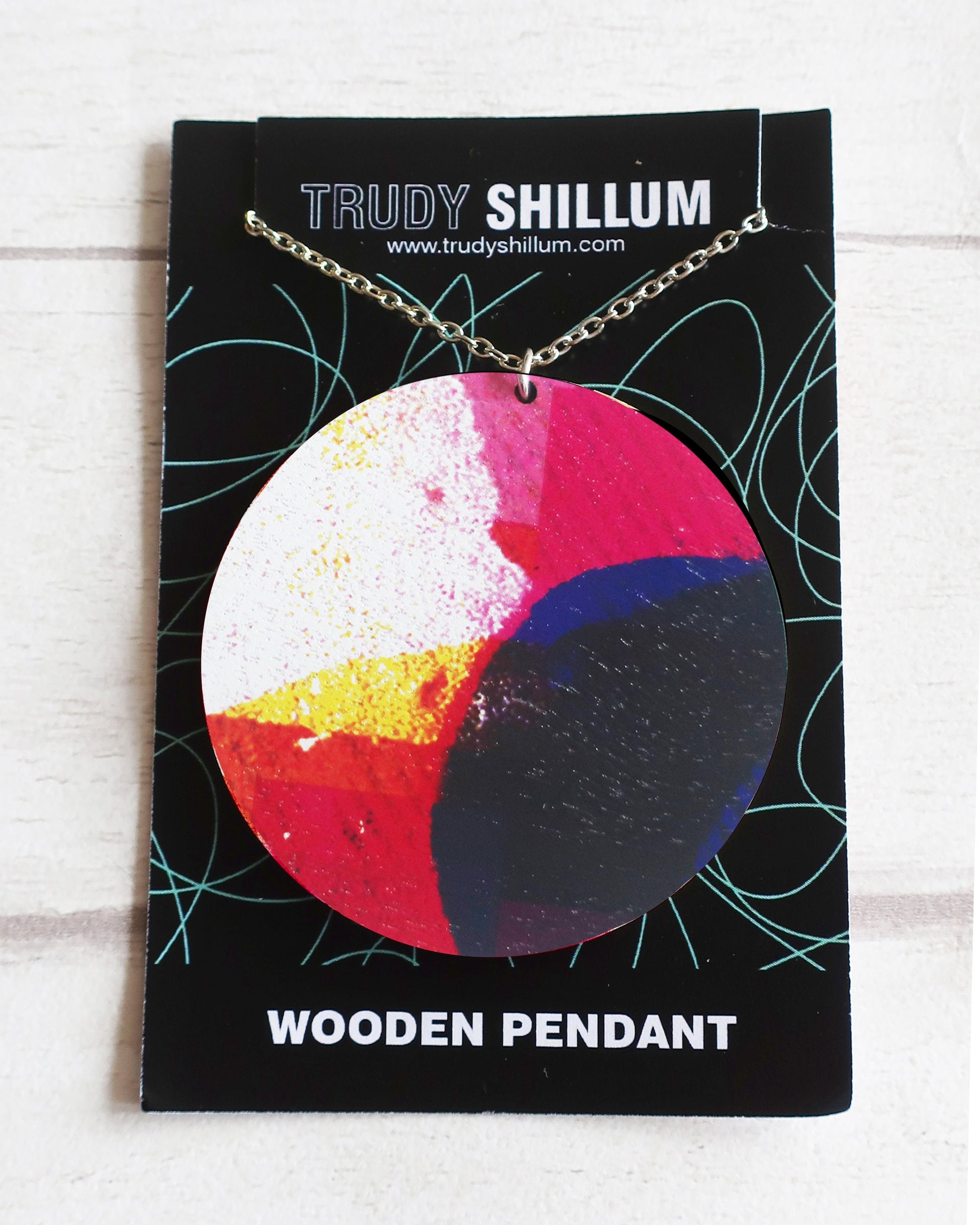 Colorful wooden pendant on a Trudy Shillum card with a white background