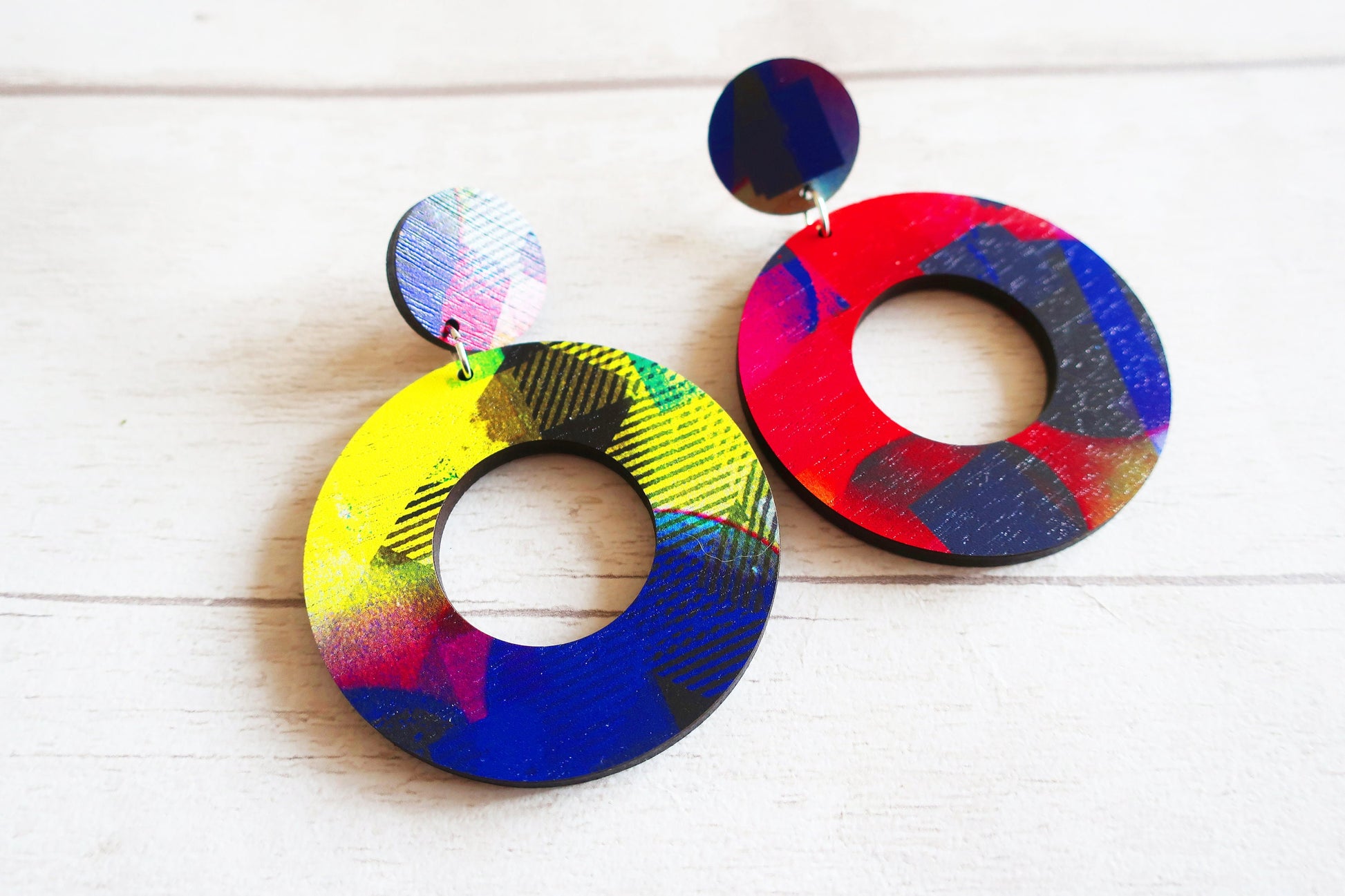 Colorful round earrings on a white wooden surface