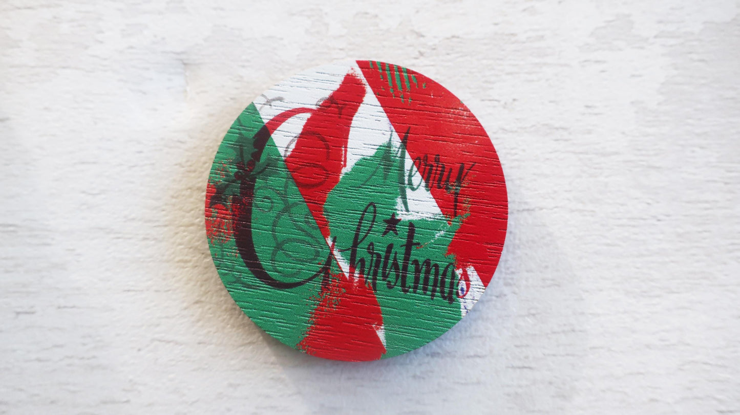 Round Christmas-themed badge  with red, green, and white design on a textured white surface