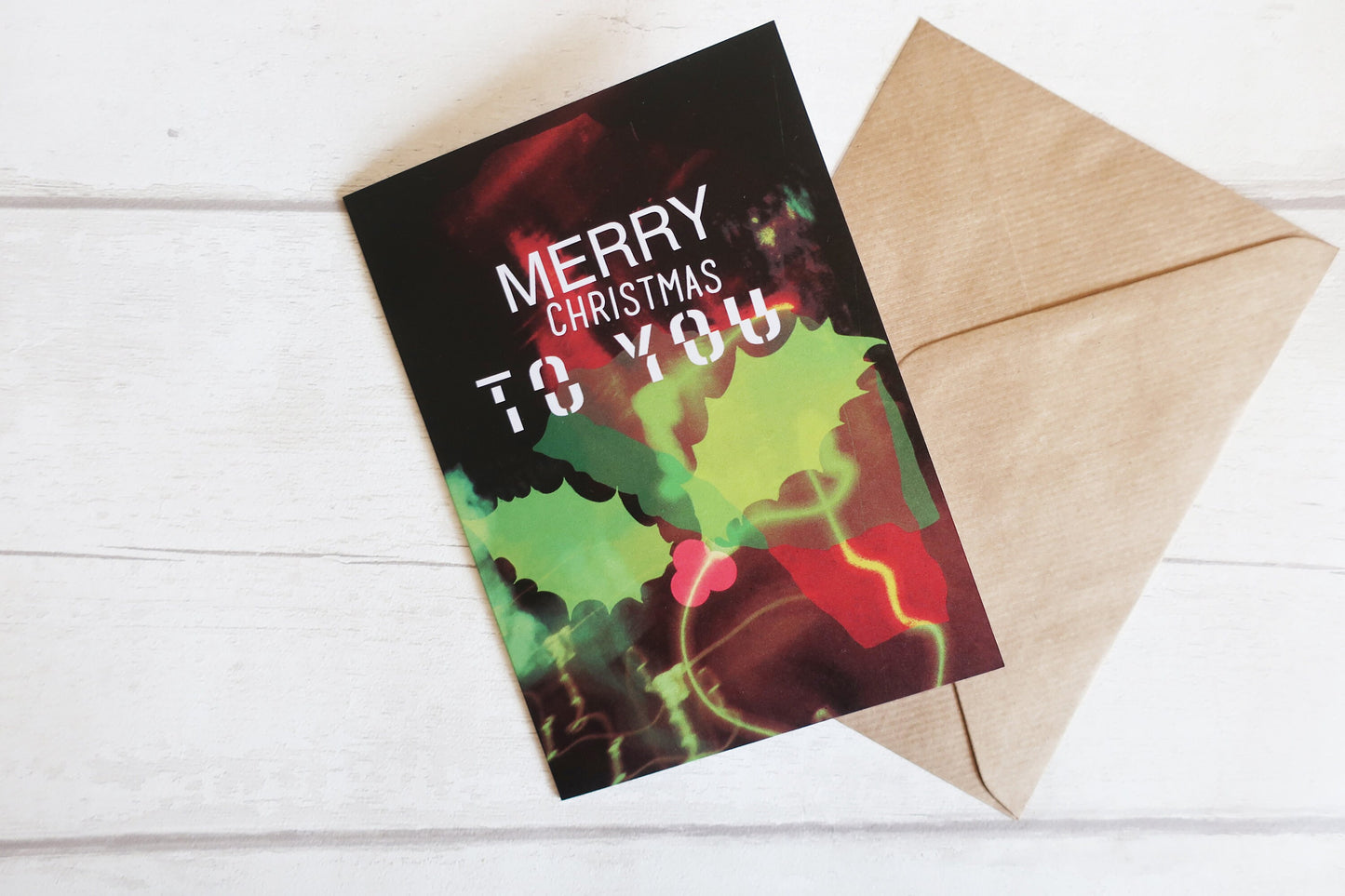 Christmas card with colorful design and 'Merry Christmas to you' text on a white wooden surface.