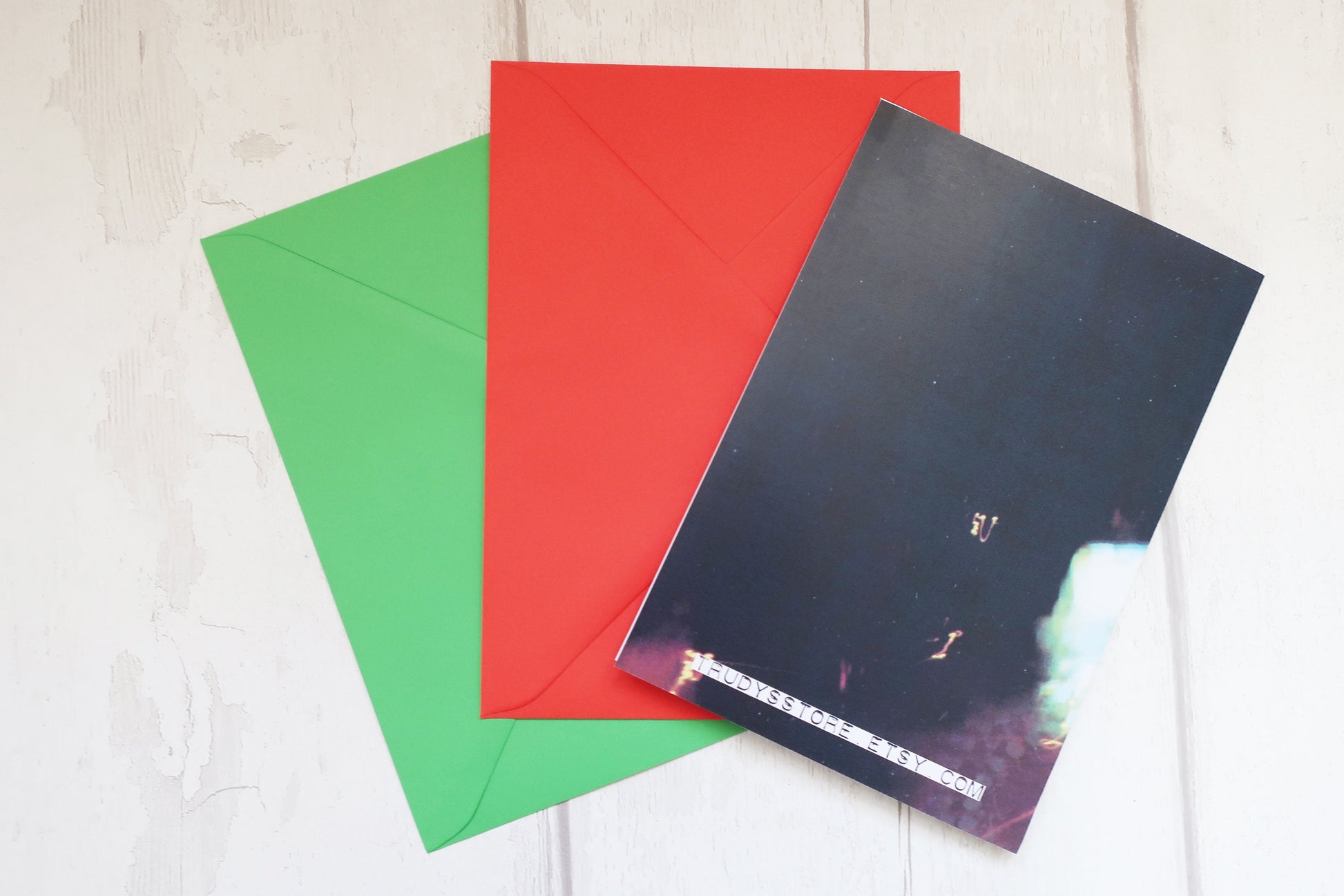 Three colorful envelopes (green, red, black) on a light wooden surface.