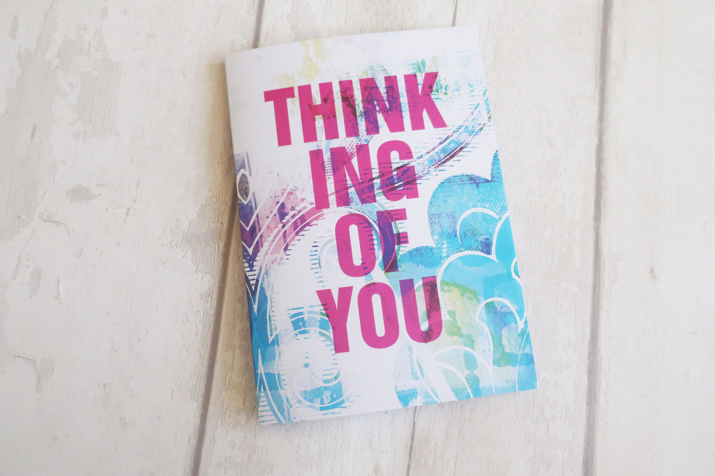 Greeting card with 'Thinking of You' text on a light wooden surface