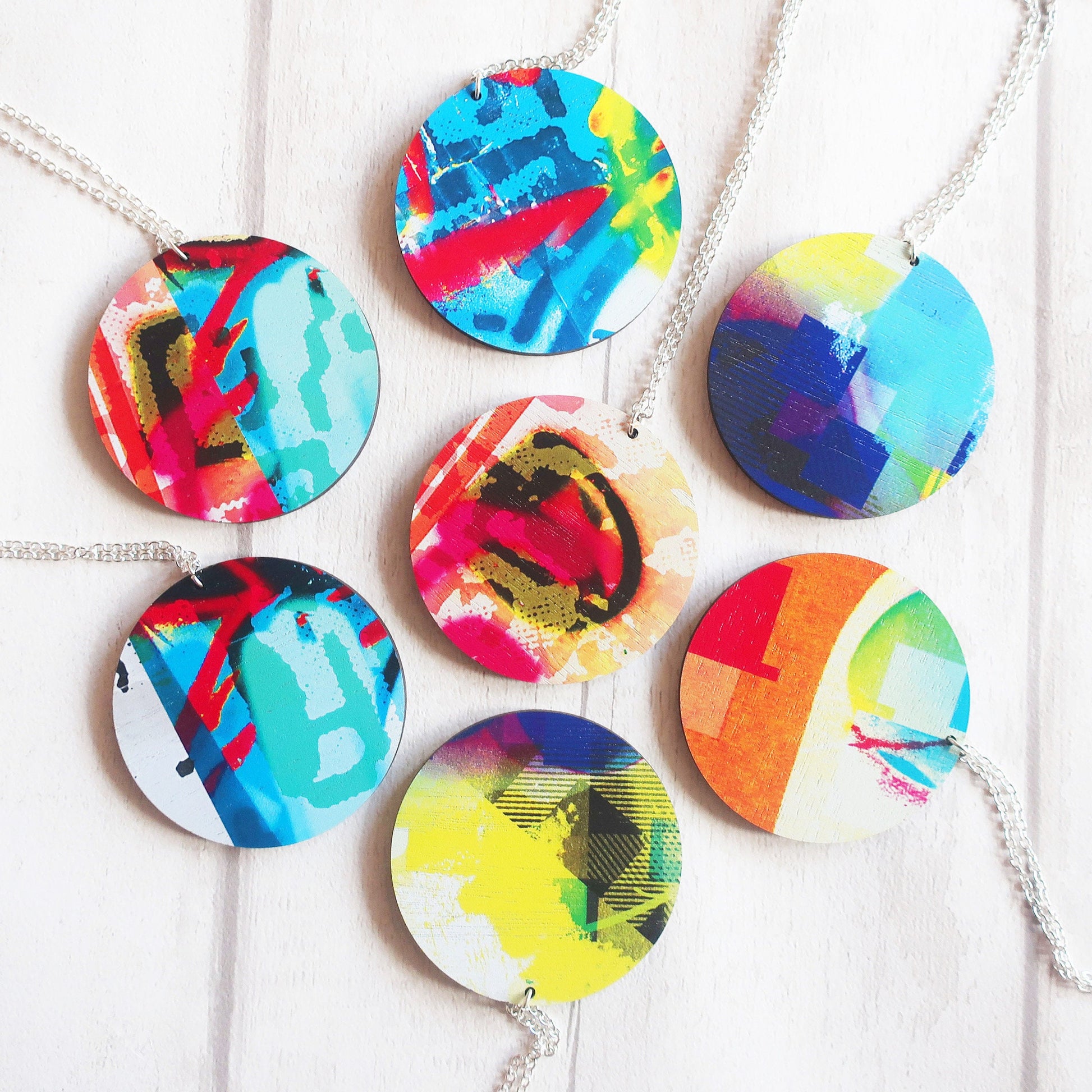 Colorful circular pendants on necklaces against a white background
