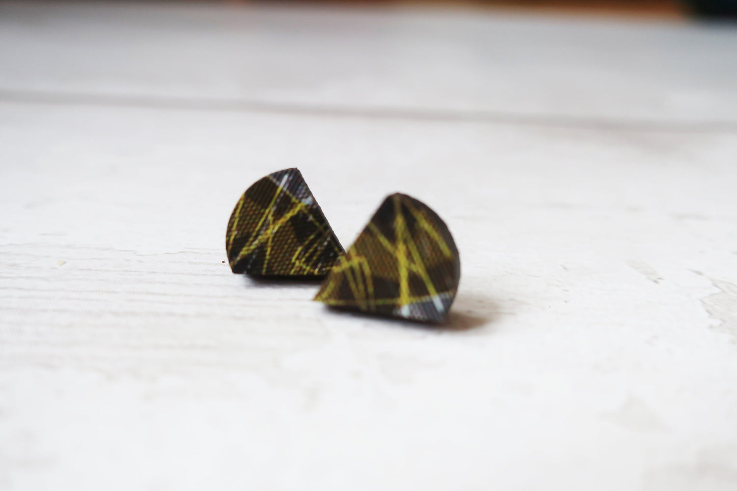 Pair of black and yellow patterned earrings on a white surface