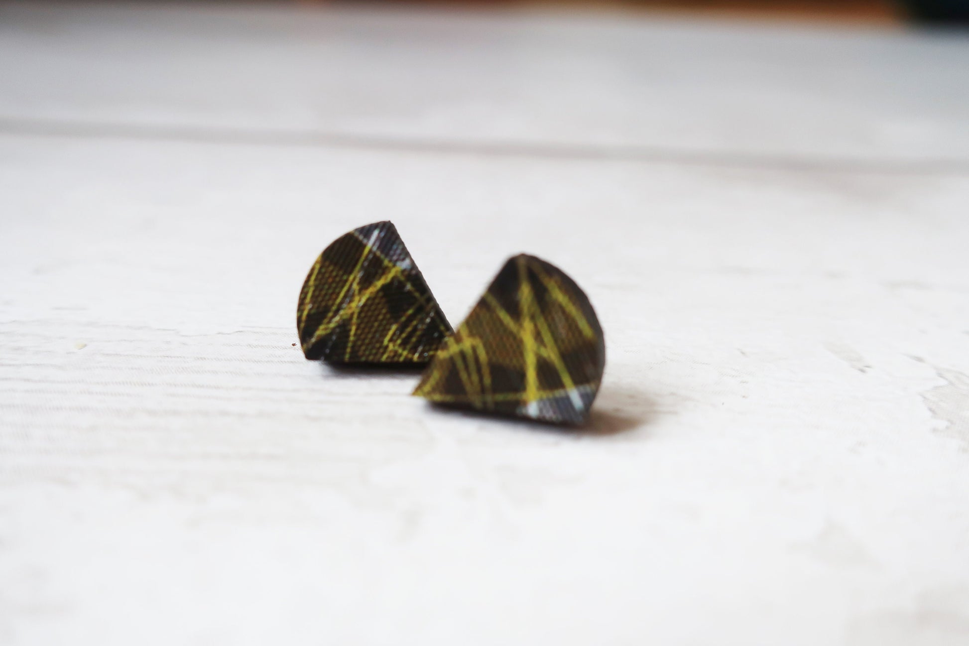 Pair of black and yellow patterned earrings on a white surface