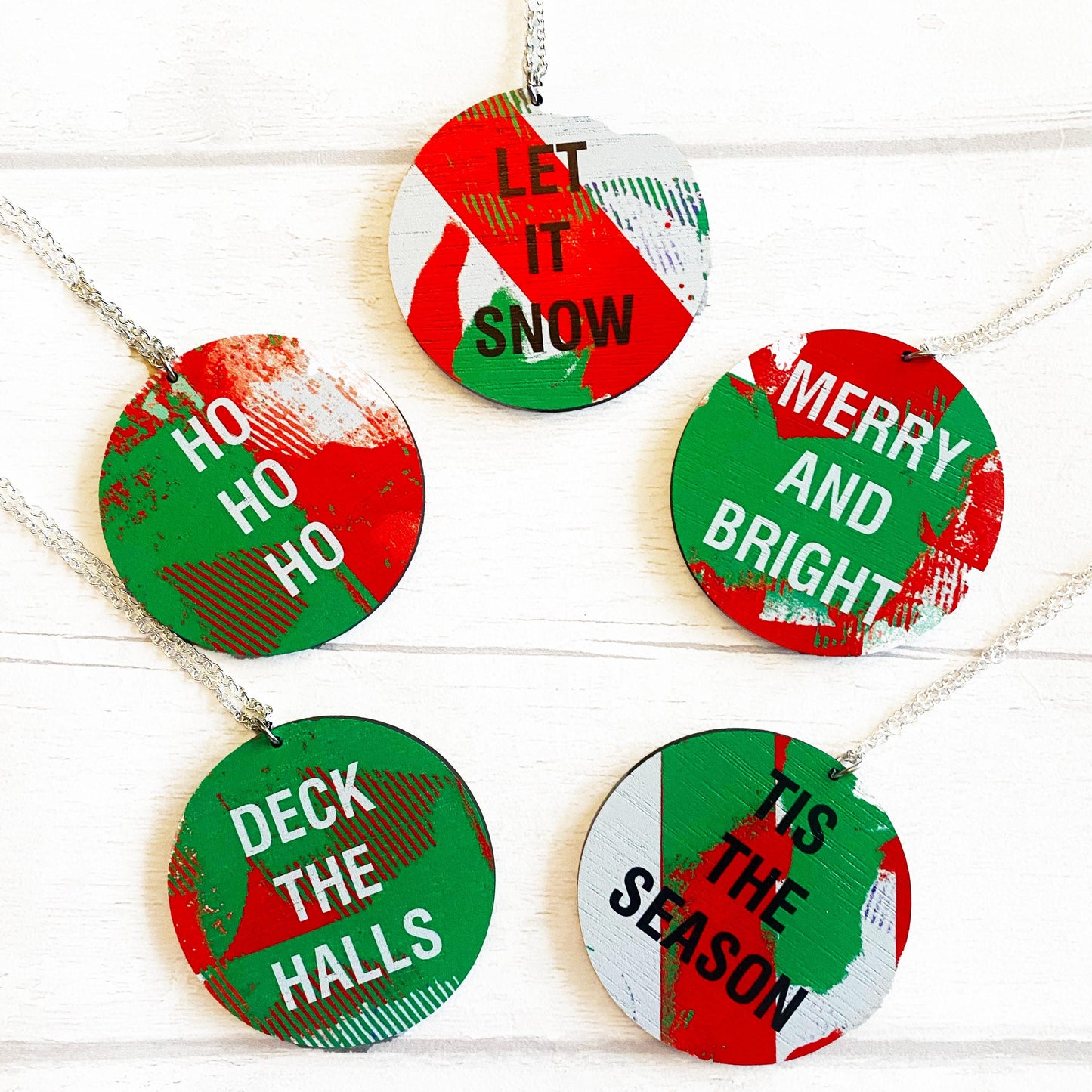 Set of Christmas-themed round necklaces with festive sayings on a white background.