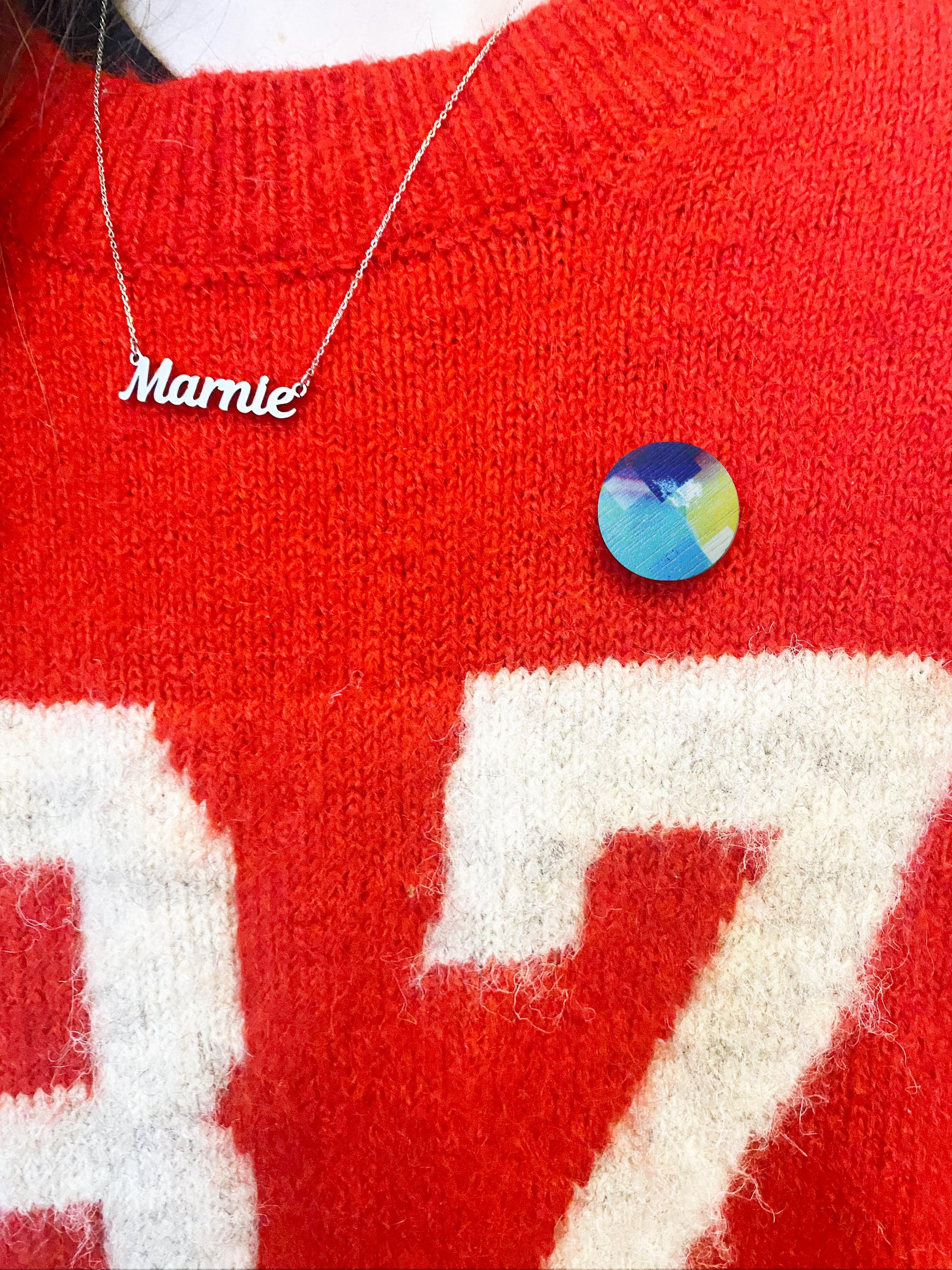 Red sweater with white text and a colorful pin badge