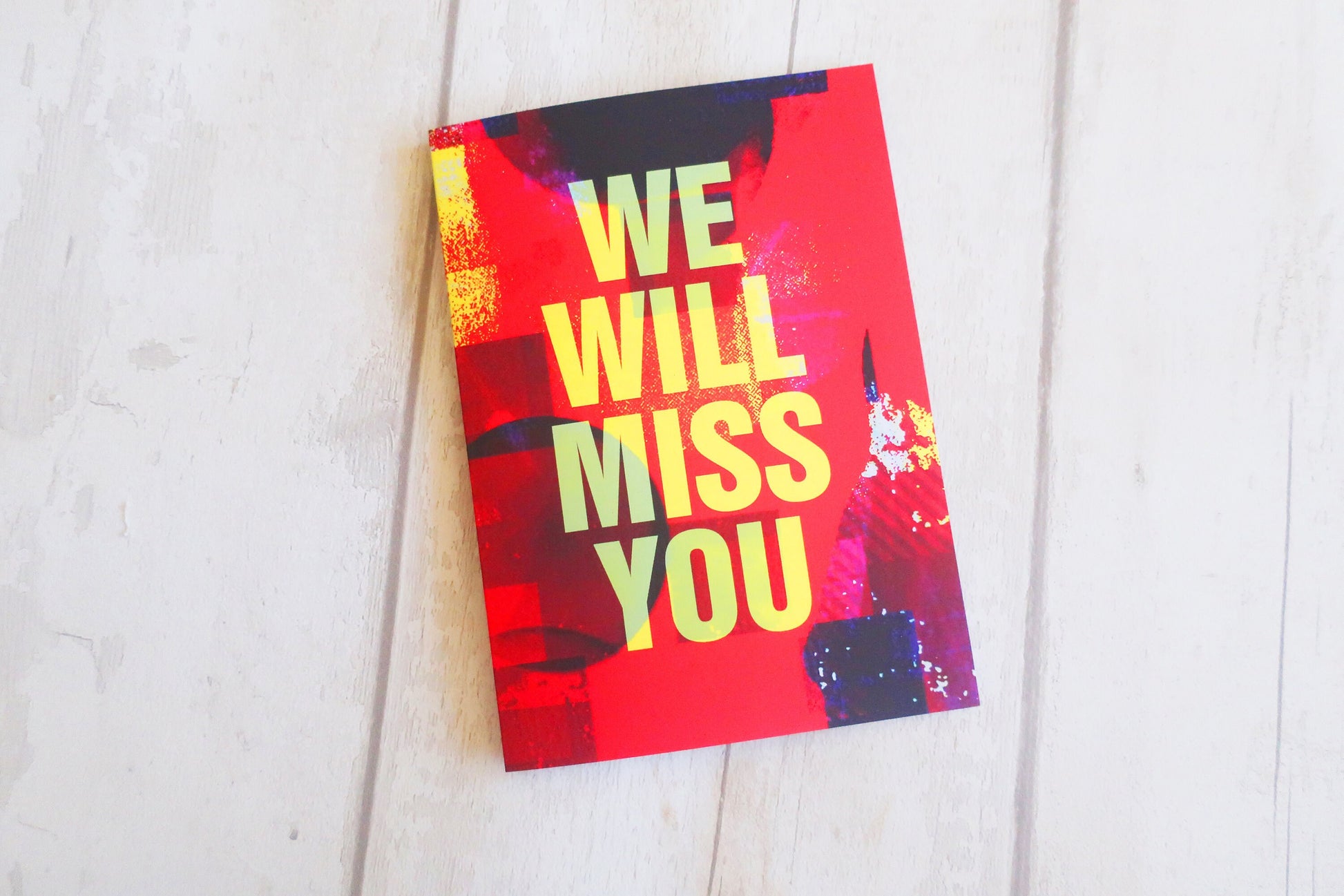 Greeting card with 'We Will Miss You' text on a white wooden surface