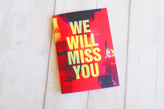 Greeting card with 'We Will Miss You' text on a white wooden surface