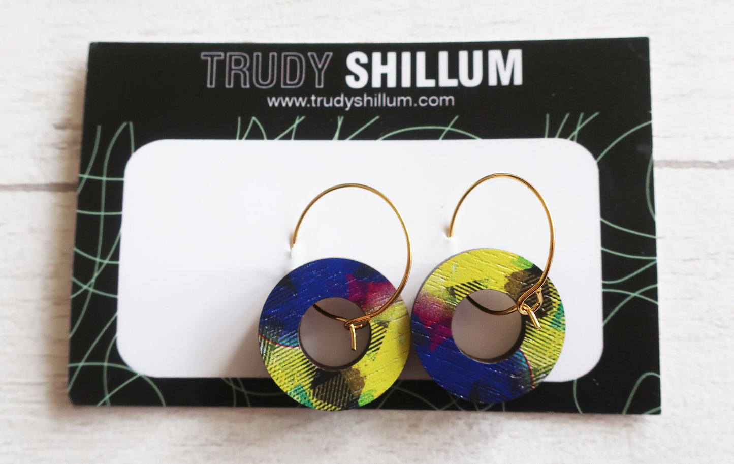 Colorful hoop earrings on a Trudy Shillum branded card.