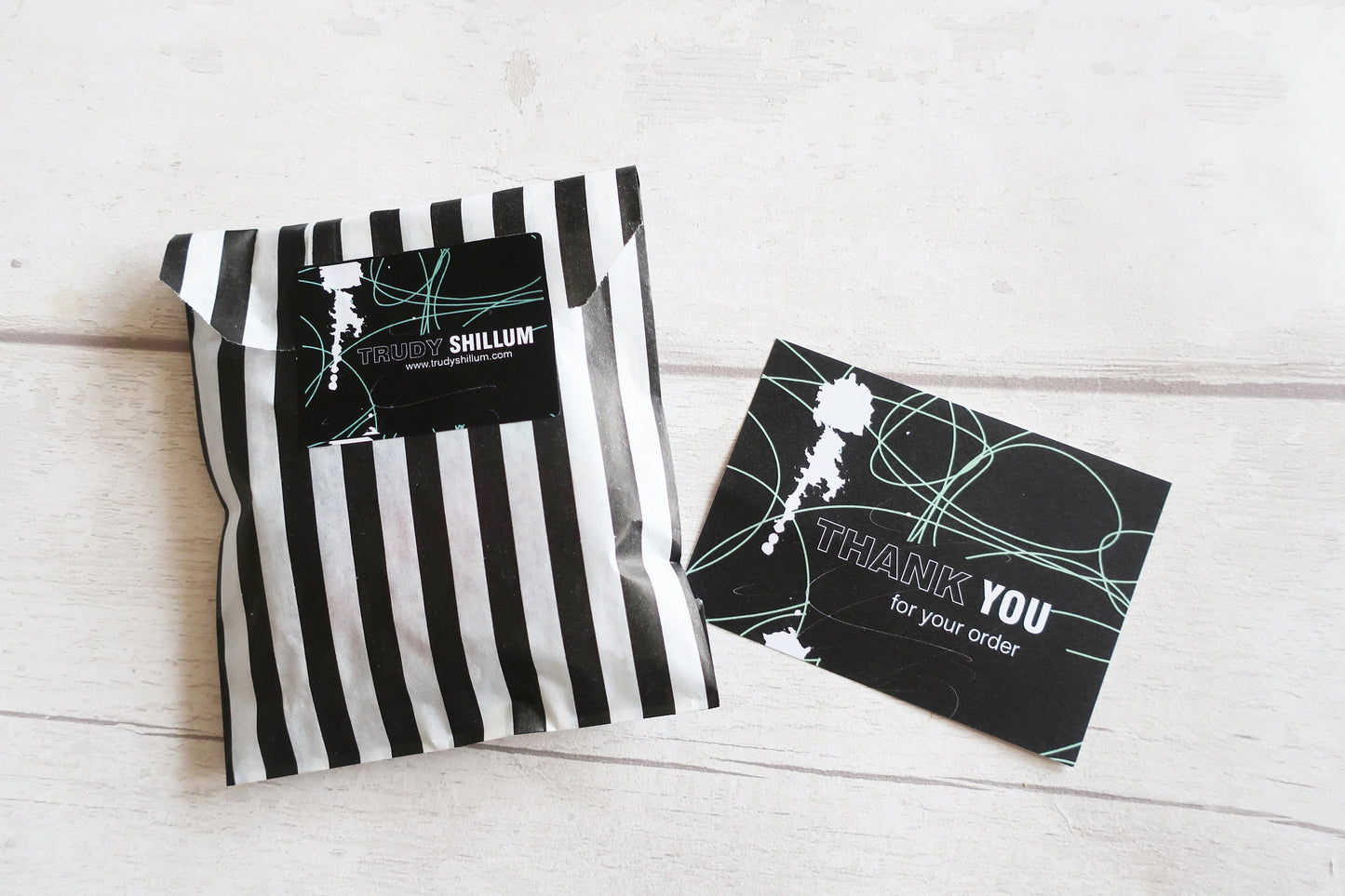 Black and white striped packaging with a card on a light wooden surface