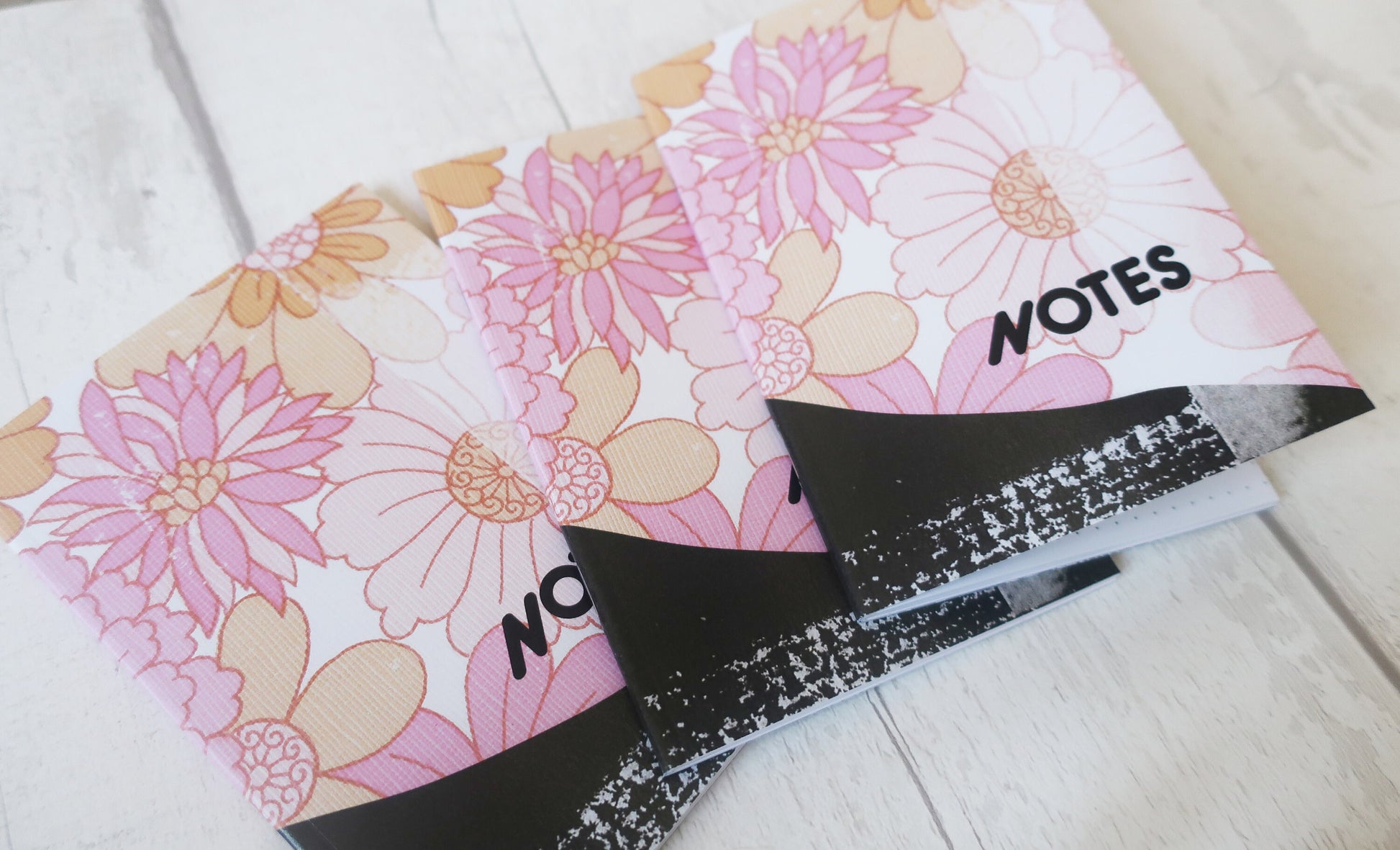 Floral notebook with 'NOTES' label on a light wooden surface