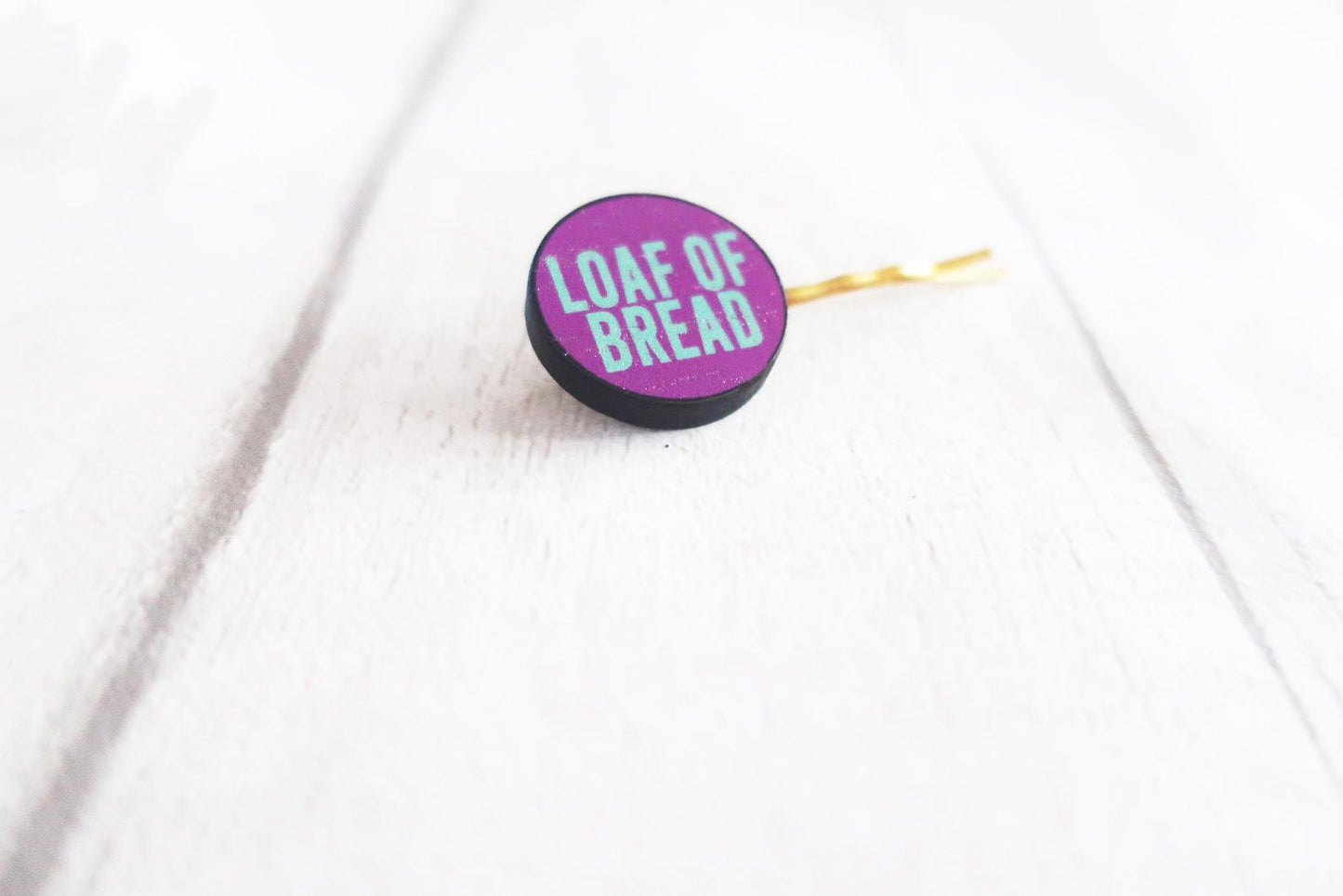 Round purple hairclip  with 'Loaf of Bread' text on a white background