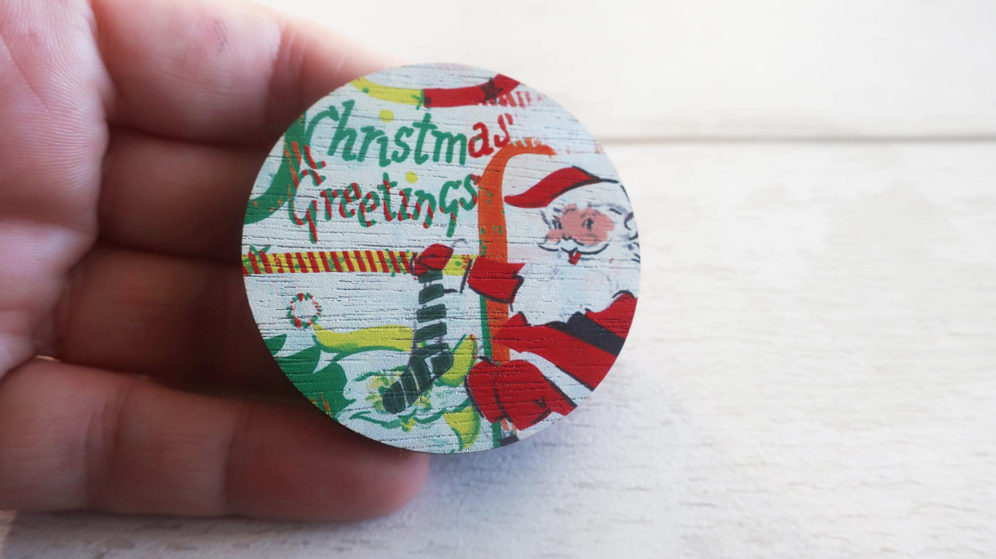 Round Christmas-themed badge  held by a hand on a light background