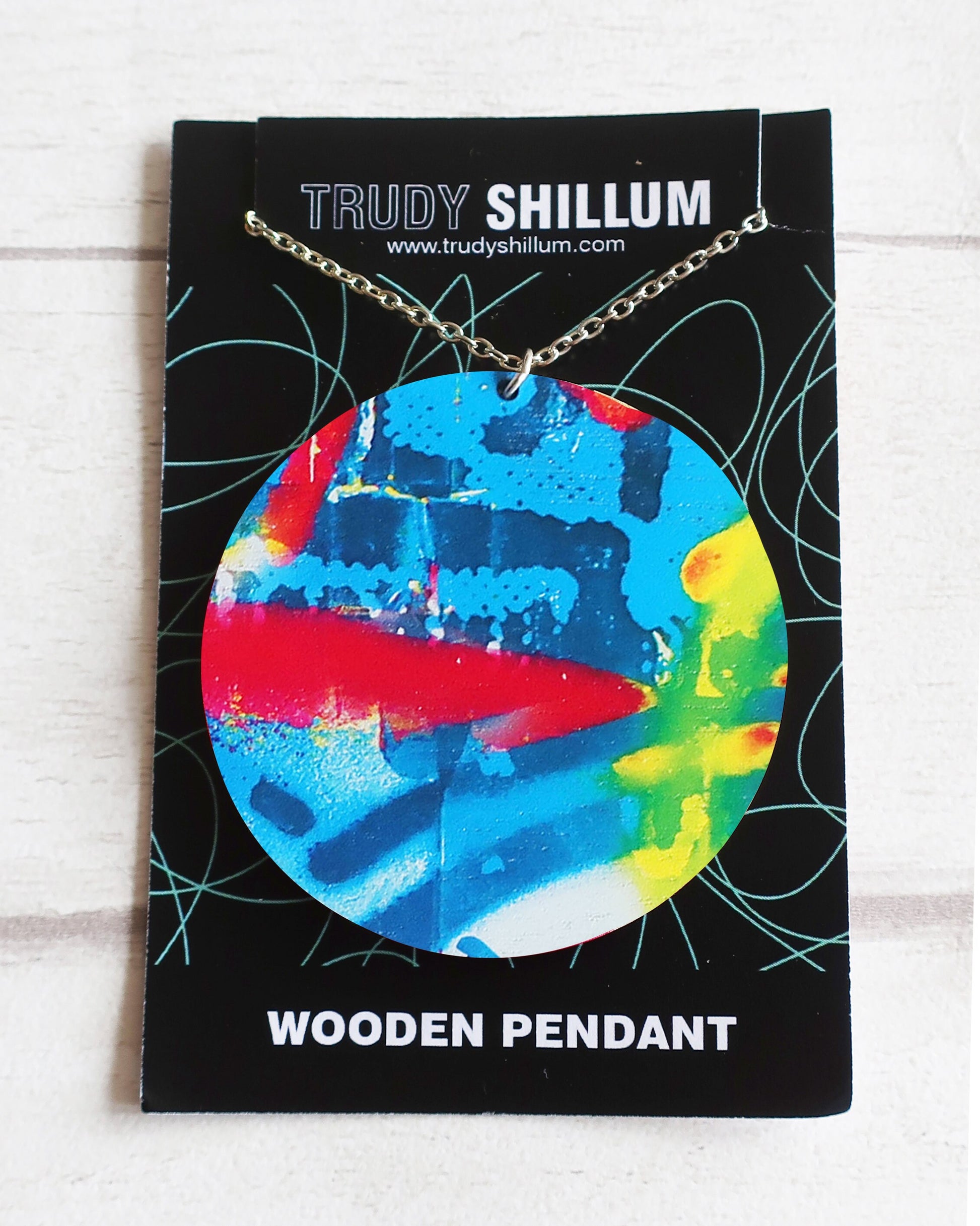 Colorful wooden pendant on a Trudy Shillum branded card