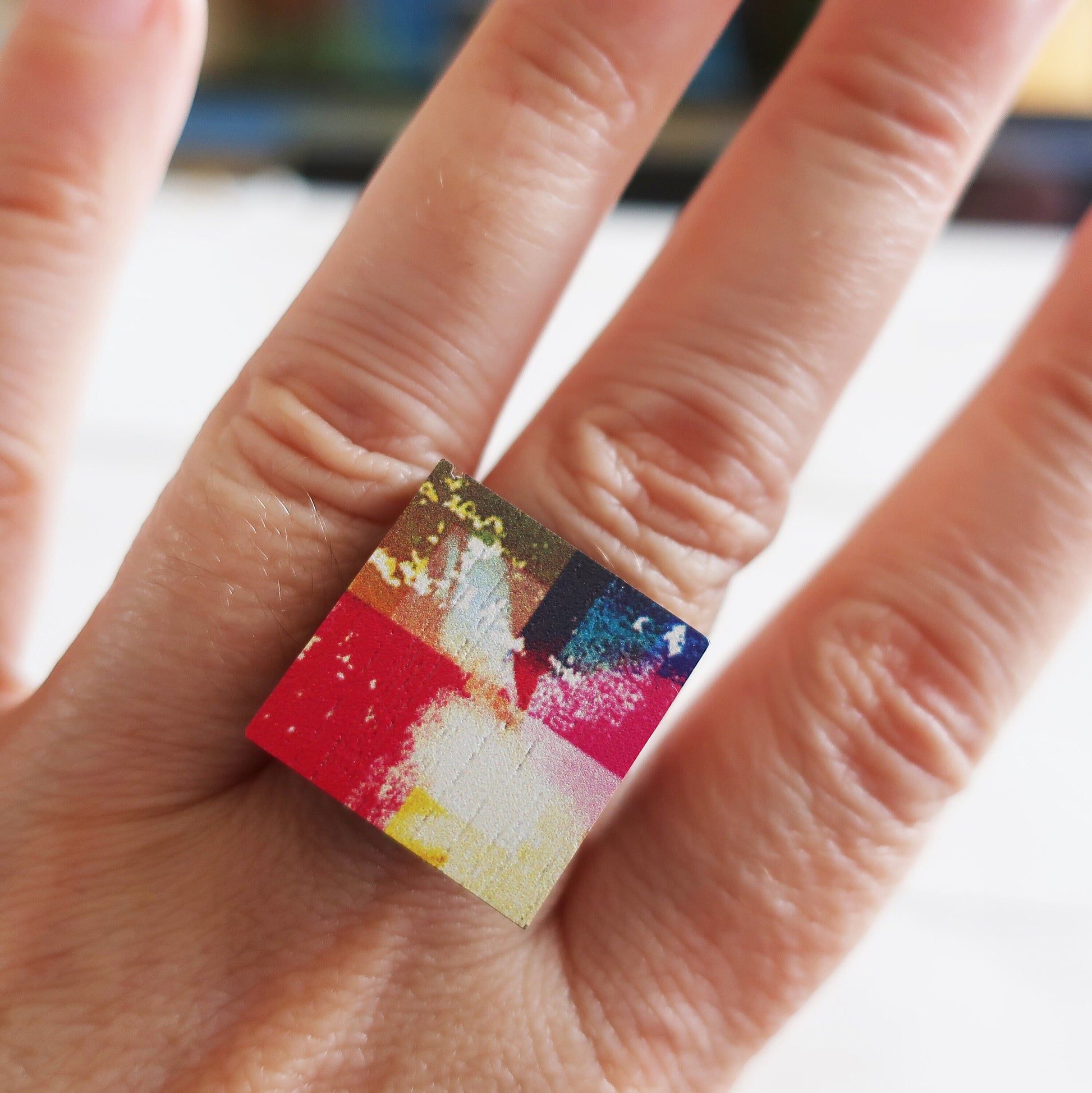 Colorful square ring on a finger with a blurred background