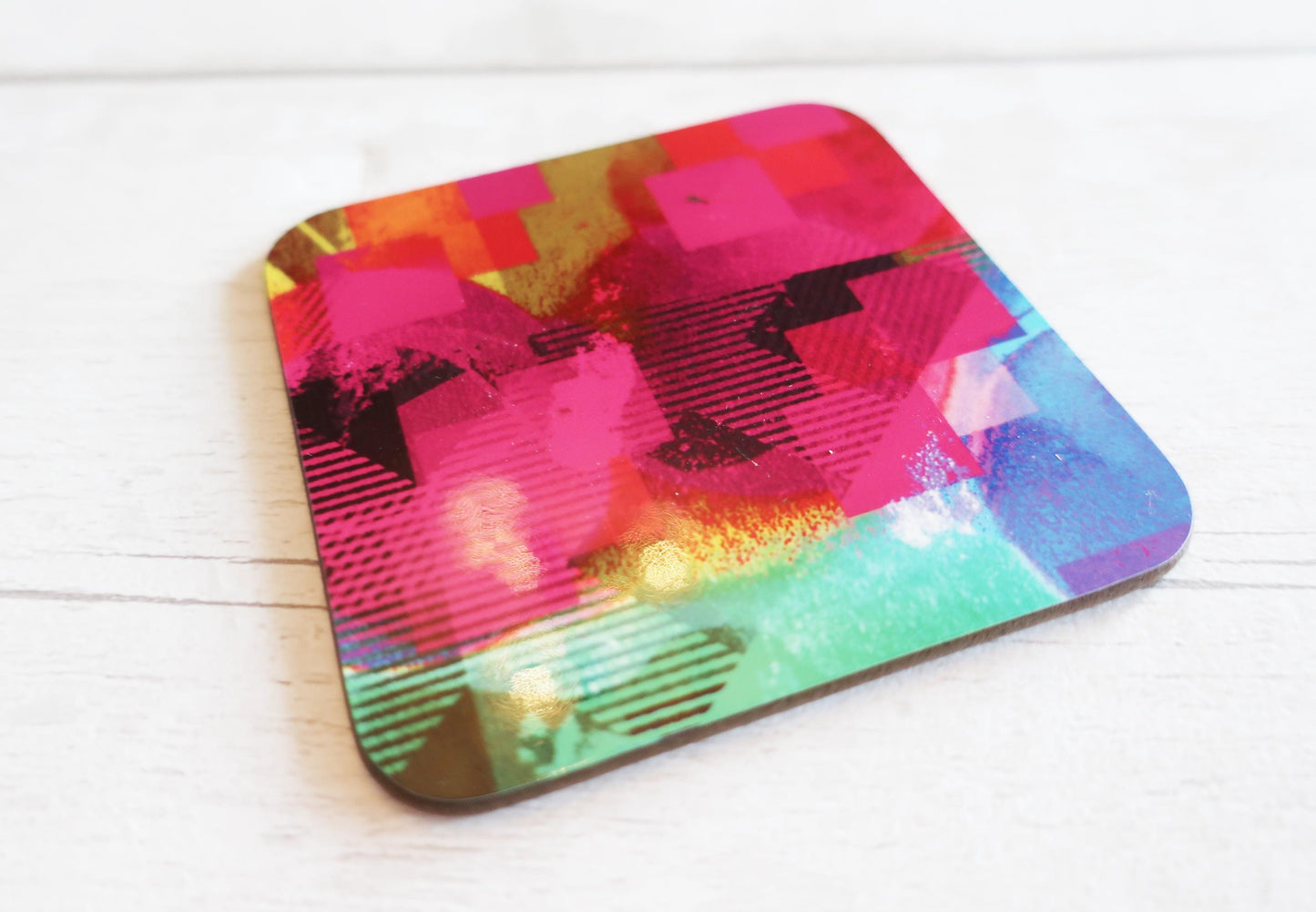 Colorful abstract design coaster on a white wooden surface