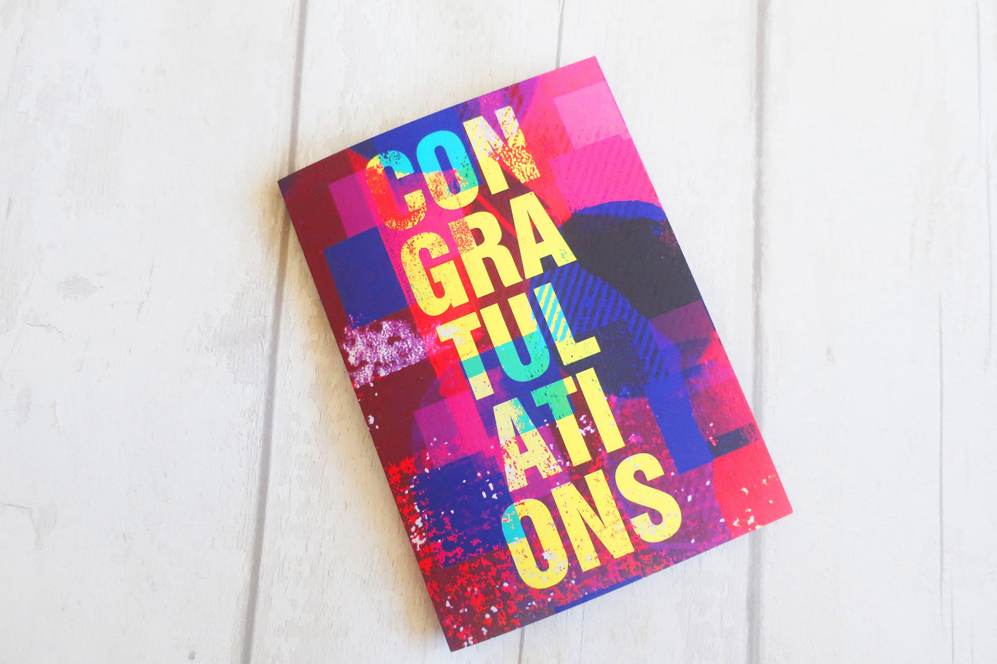 Colorful card with 'Congratulations' text on a white wooden surface
