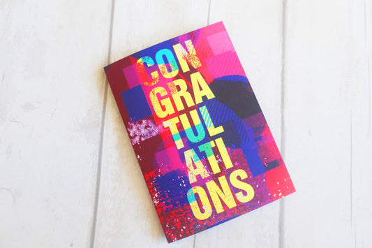 Colorful card with 'Congratulations' text on a white wooden surface