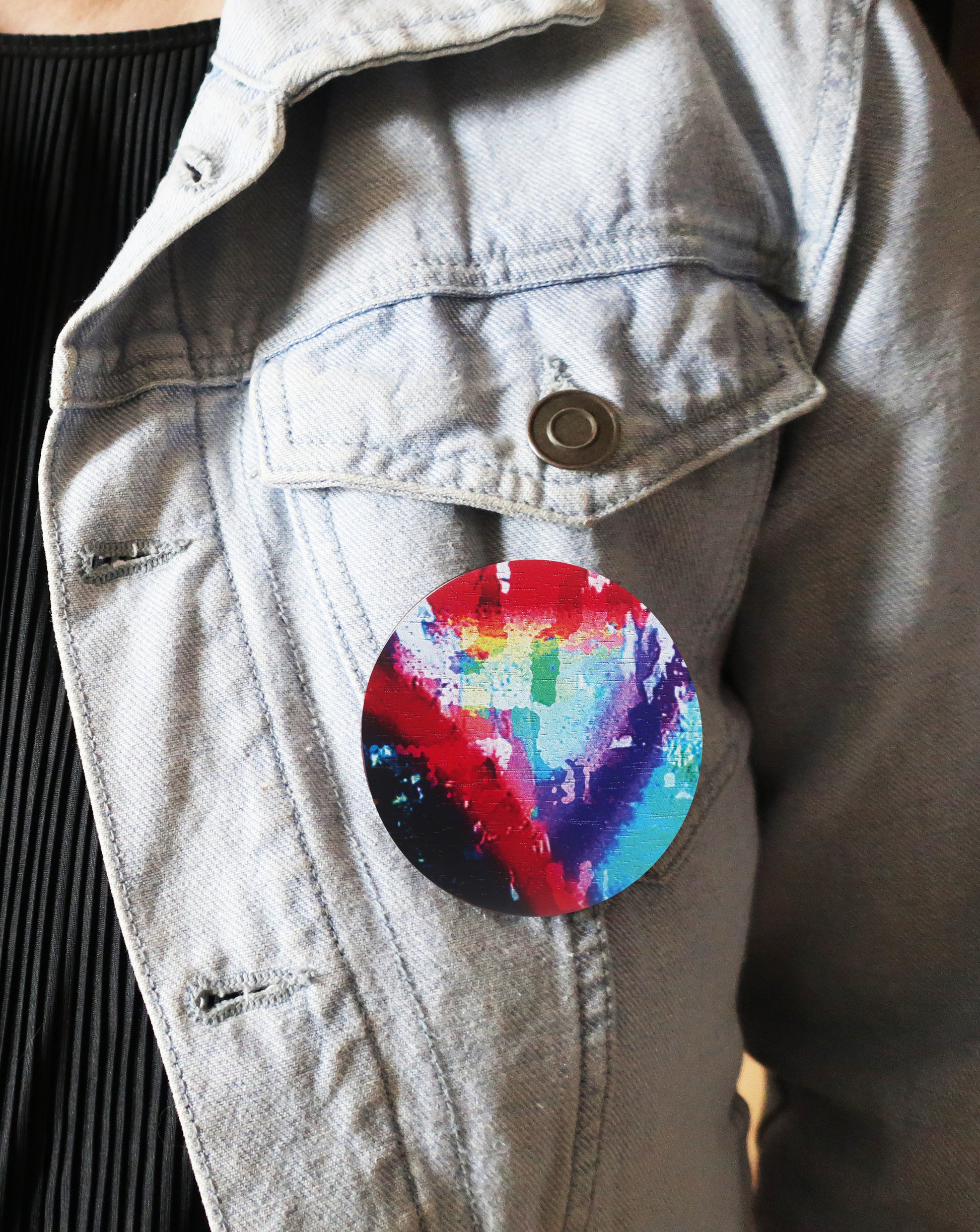Colorful tie-dye brooch on a light blue denim jacket