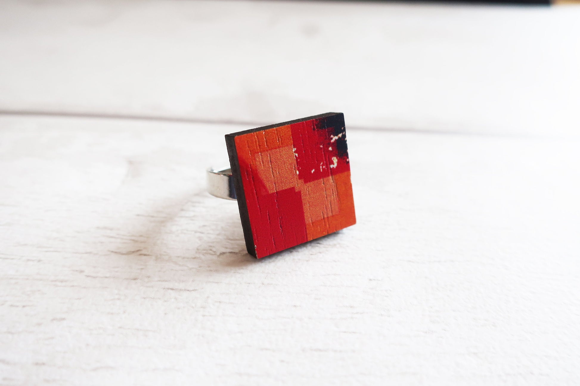 Square ring with red and black pattern on a white surface