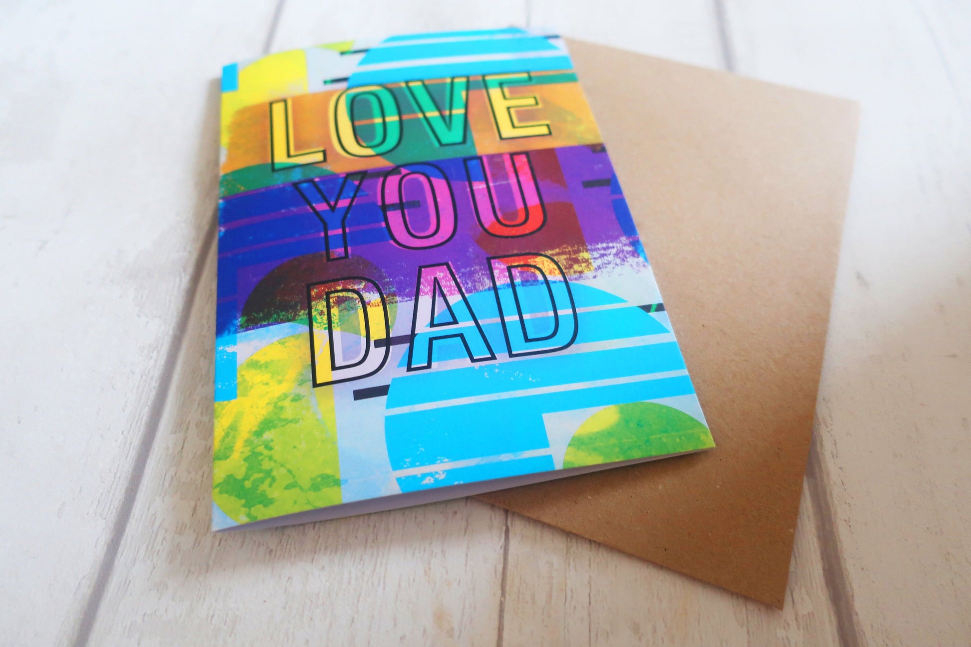 Colorful card with 'Love You Dad' text on a wooden surface