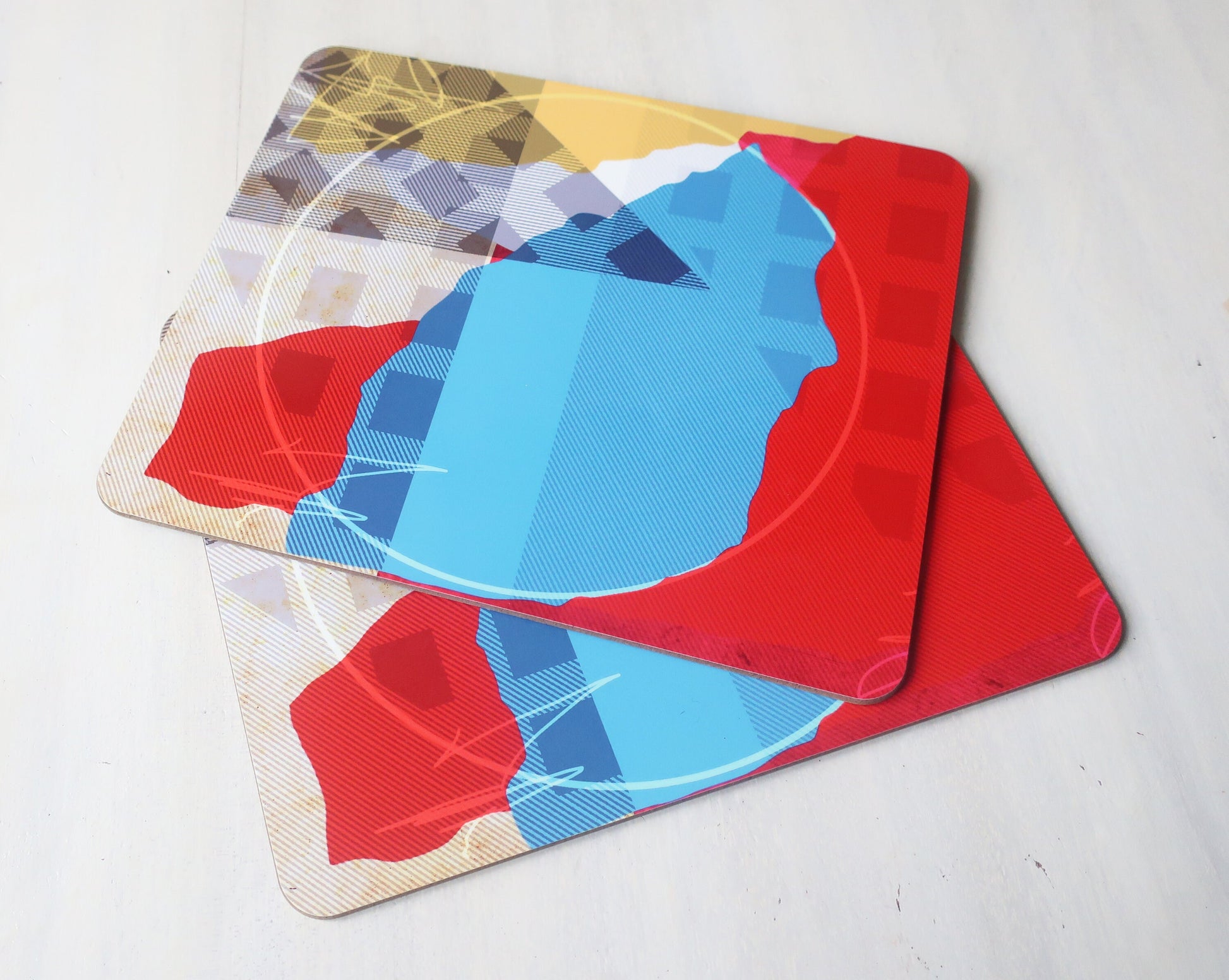 Set of colorful geometric placemats on a light gray surface