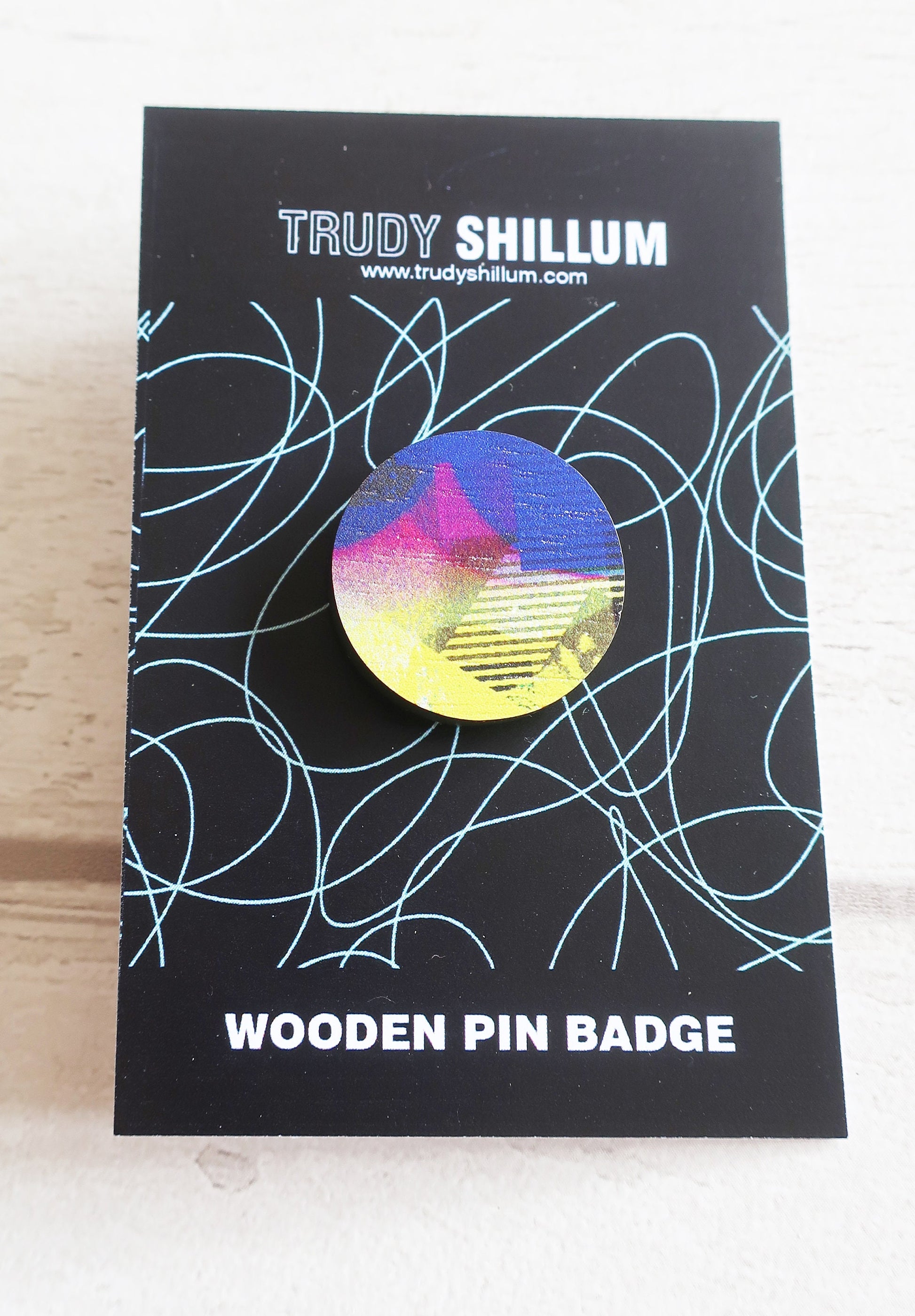 Trudy Shillum wooden pin badge packaging with abstract design on a black background