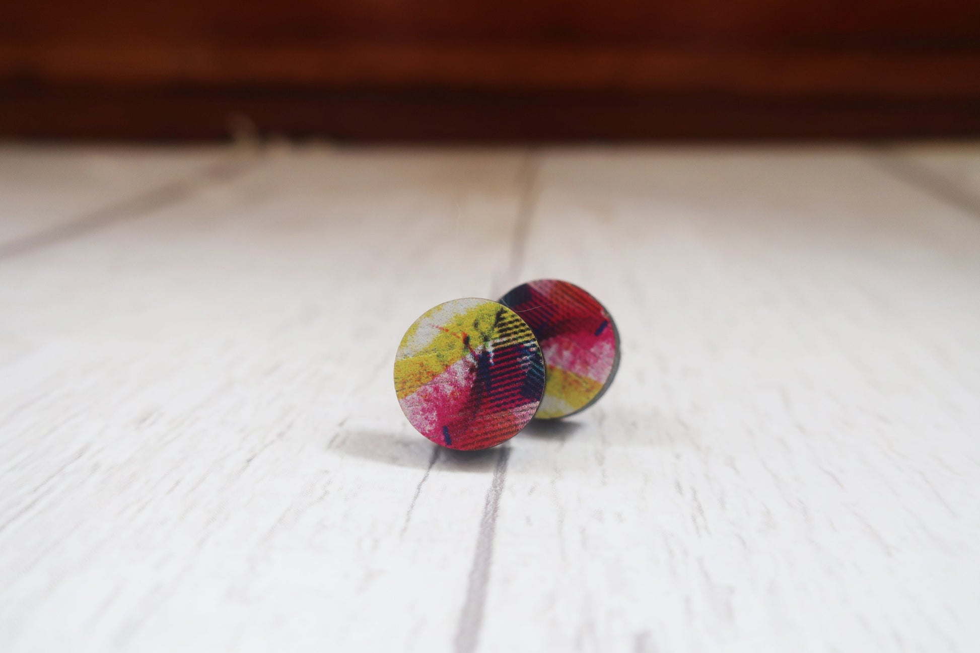 Colorful tie-dye patterned earrings on a white surface