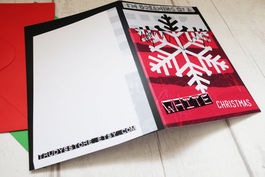Christmas card with a snowflake design and red envelope on a light surface