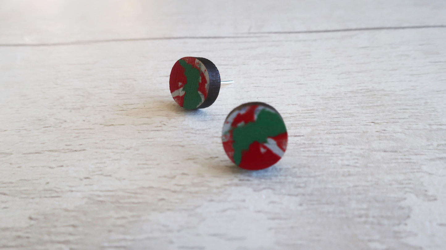 Round earrings with red and green design on a light wooden surface