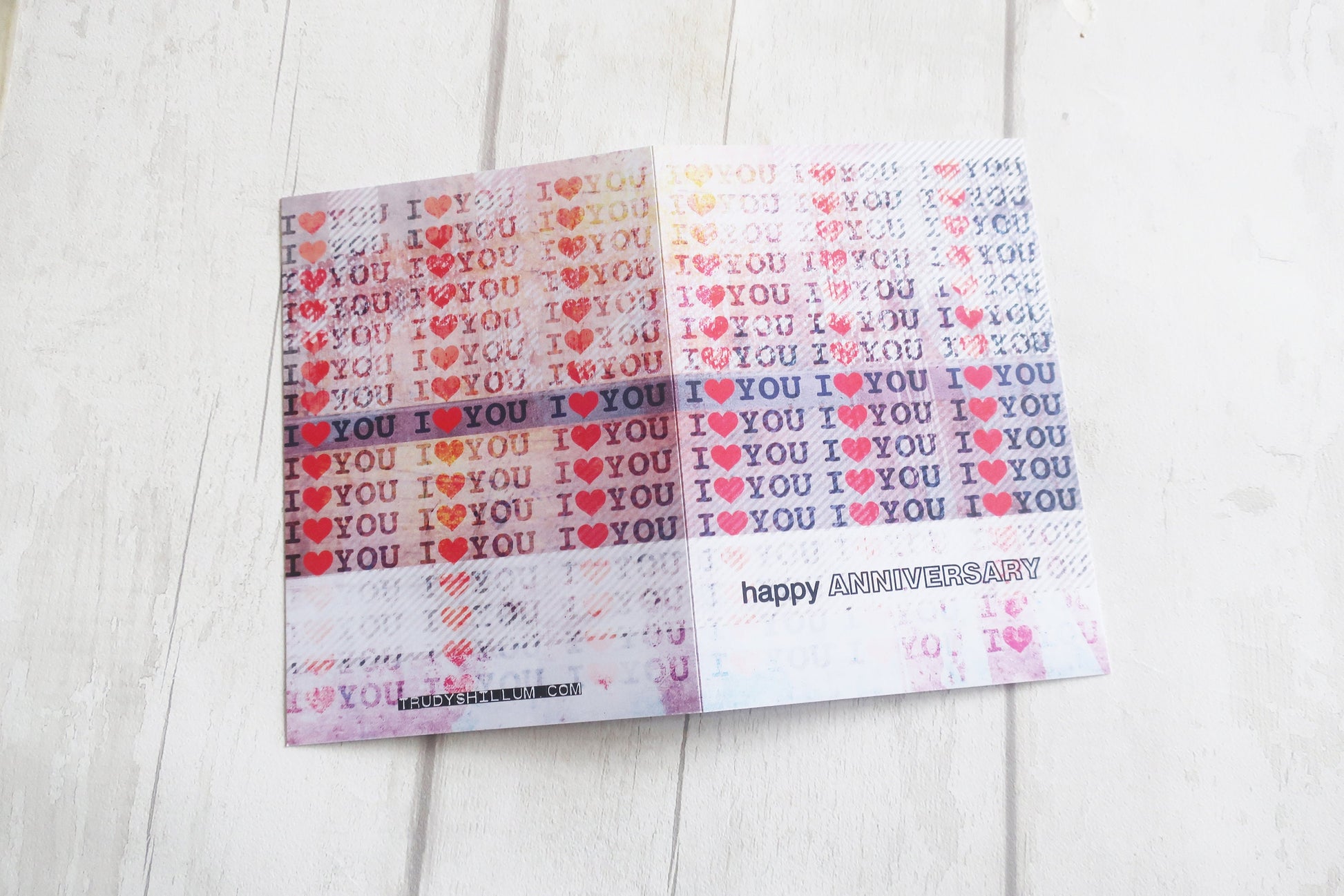 greeting card with 'I love you' and 'Happy Anniversary' text on a light wooden surface.