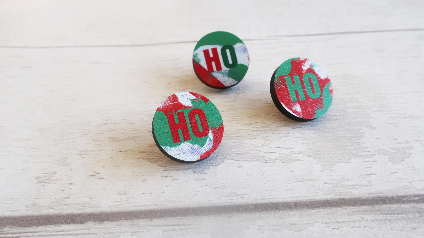 Three circular red and green pin badges with 'HO' text on a light wooden surface.